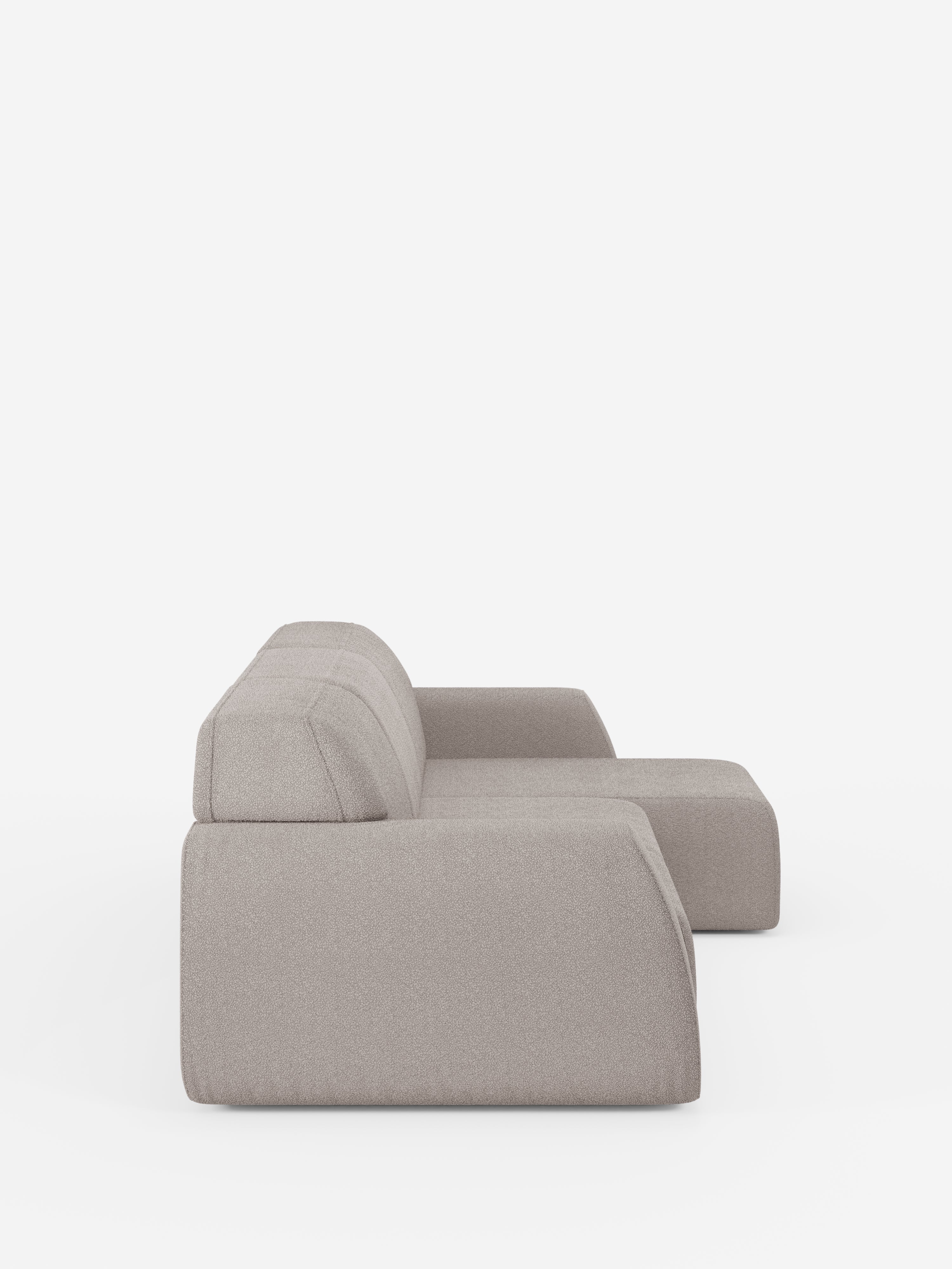 Una vista laterale del divano angolare Orbit con penisola reversibile e tutte le sedute allungabili in tessuto smacchiabile effetto cotone T33 di divitt.sbs, caratterizzato da un design moderno in grigio chiaro con linee pulite e cuscini dal profilo basso, su uno sfondo bianco a tinta unita. Questo divano morbido e confortevole è privo di gambe a vista, il che ne esalta l’aspetto minimalista.