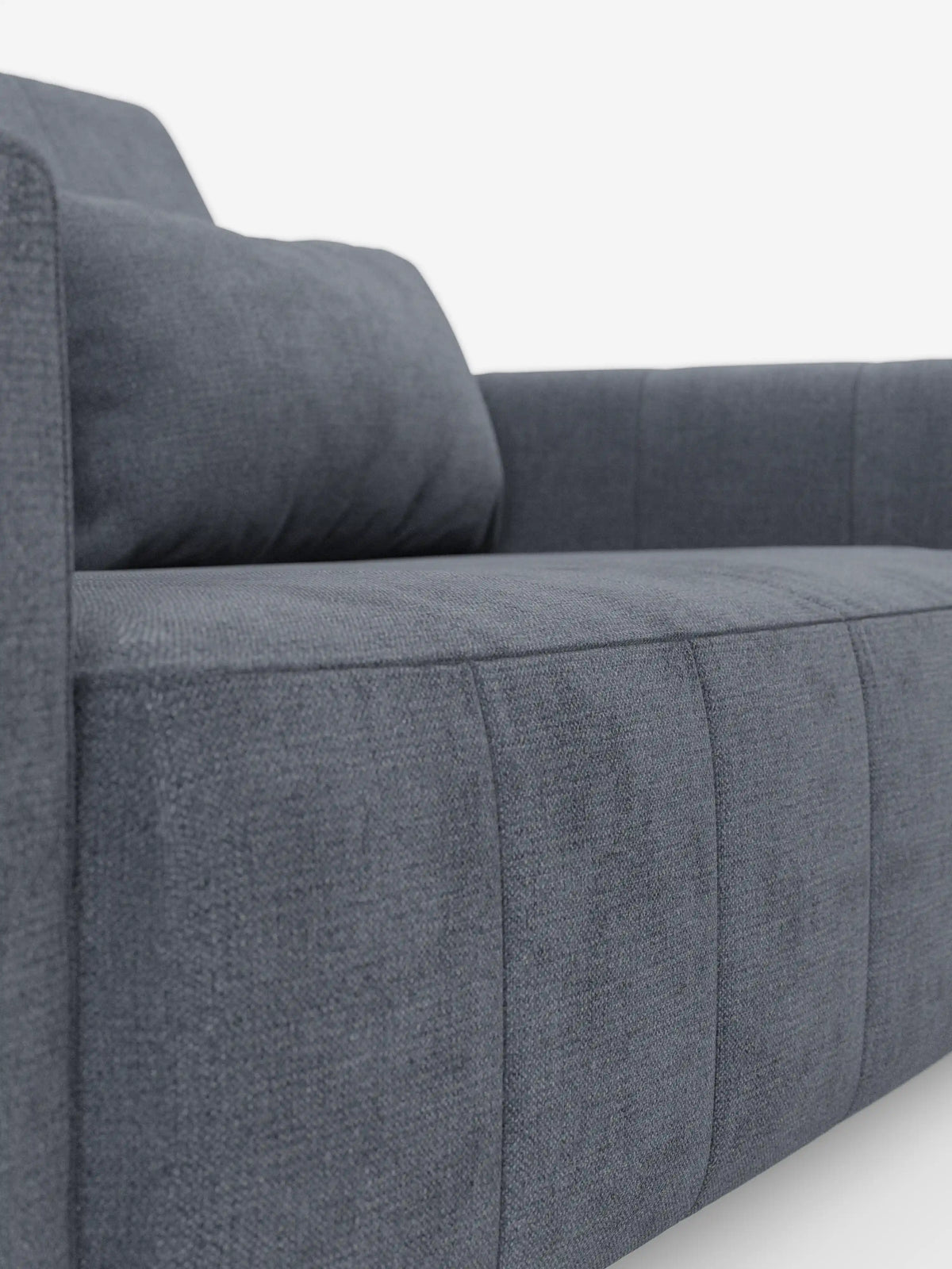 Primo piano del divano dorico a 3 posti con sedute allungabili tramite meccanismo relax elettrico di divitt.sbs, caratterizzato da un moderno rivestimento in tessuto grigio scuro smacchiabile T23 con trama leggermente ruvida. Il divano presenta braccioli squadrati e cuciture a vista, che risaltano sullo sfondo bianco a tinta unita, con l’angolazione che mette in risalto la seduta e uno dei braccioli.