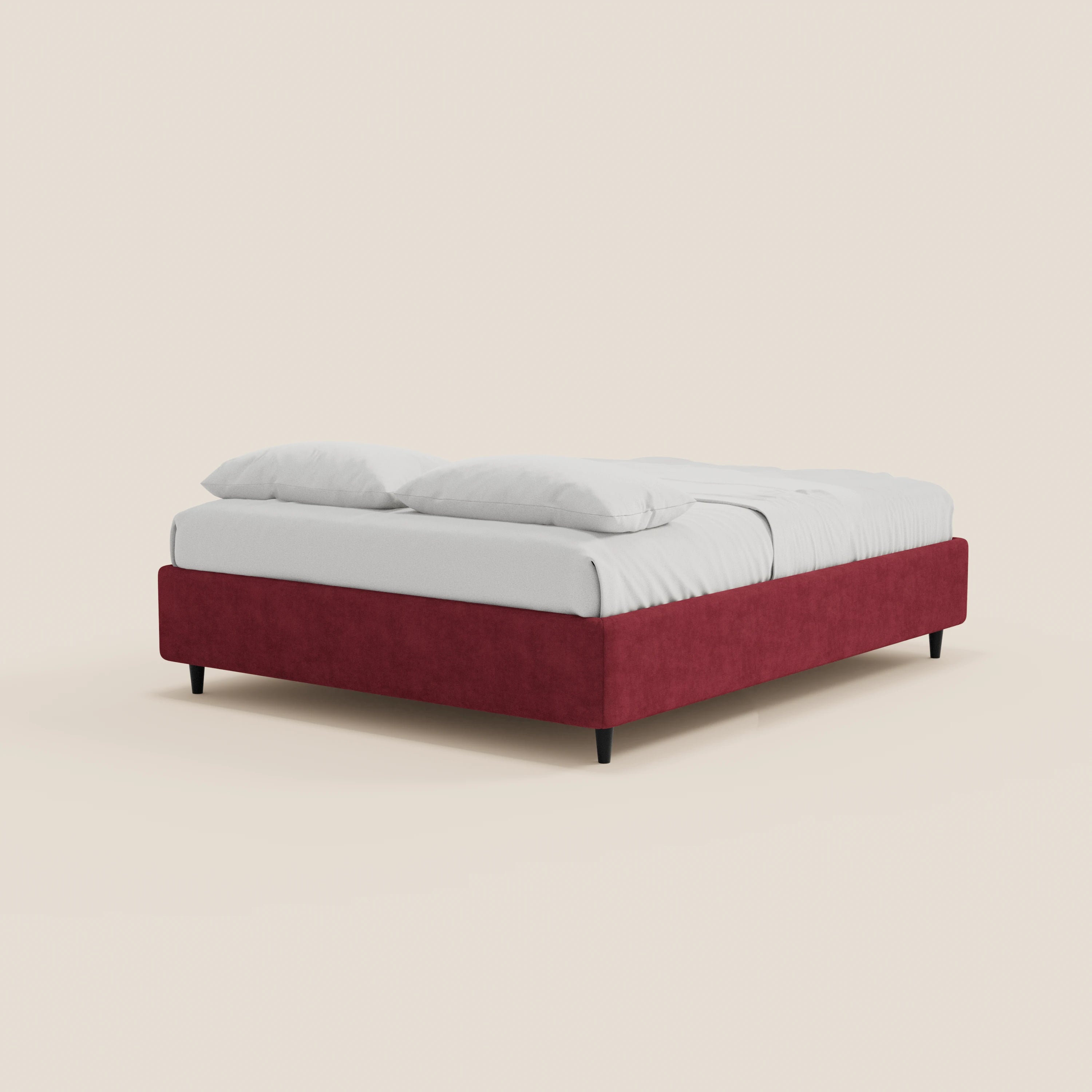 Il letto sommier imbottito con contenitore ERON di Letti.store, caratterizzato da una struttura in tessuto impermeabile rosso certificato Oeko-Tex senza testiera, gambe nere e biancheria da letto bianca con due cuscini, è esposto su uno sfondo beige chiaro.
