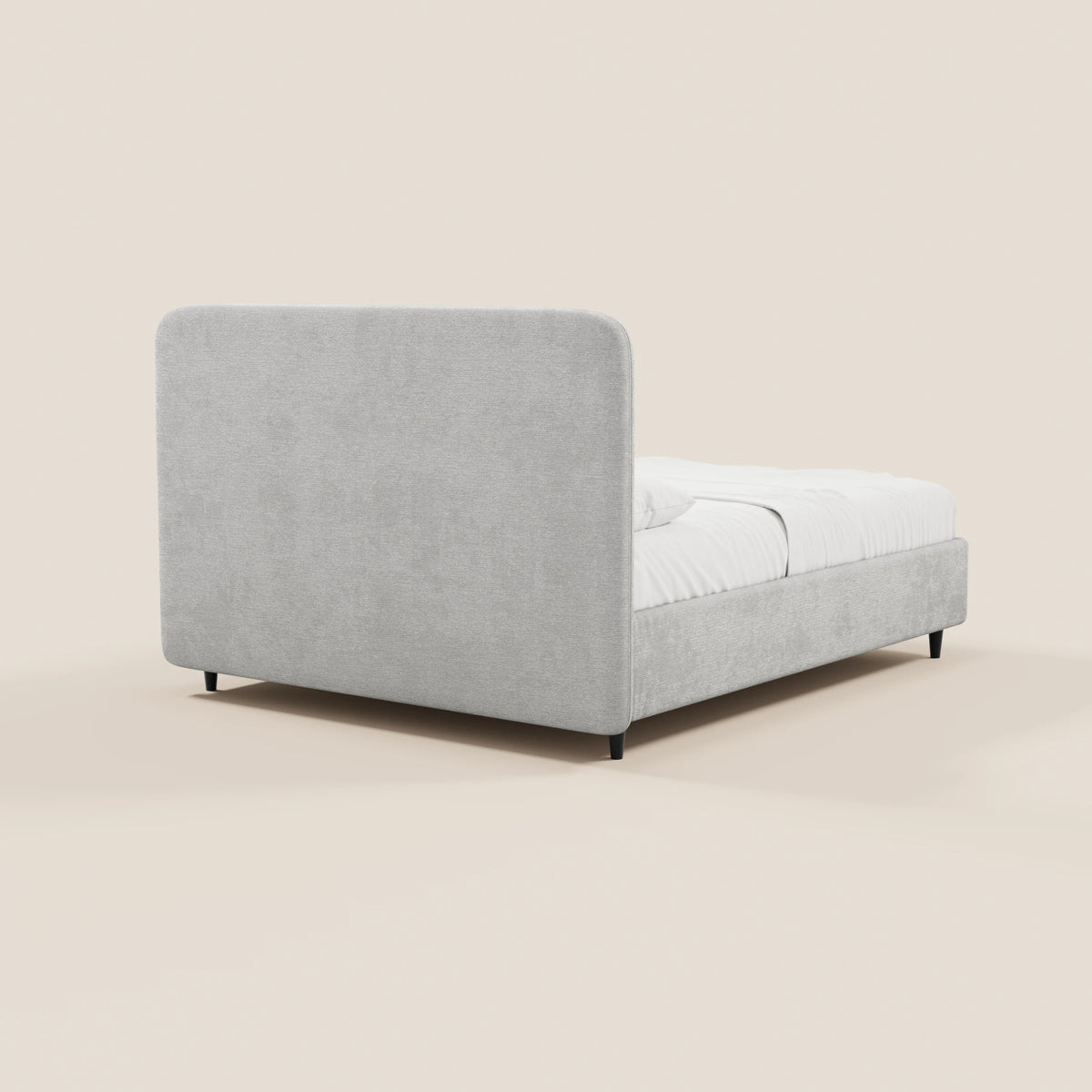 Il letto KAELOS minimal imbottito di Letti.store presenta una testiera alta e arrotondata, rivestita in ciniglia grigio chiaro, con telaio in tinta, gambe alte nere e vano contenitore. Nella foto è raffigurato con la biancheria da letto bianca ben rifatta su uno sfondo a tinta unita.