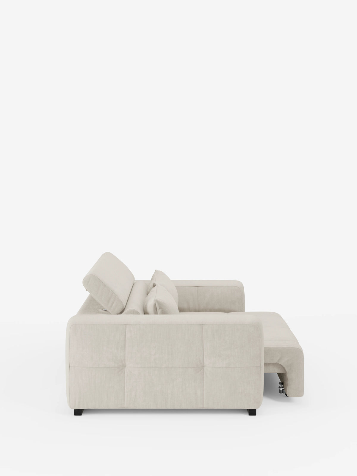 Vista laterale del divano Monarch con relax elettrico per l'allungamento delle sedute e poggiatesta reclinabile di divitt.sbs, rivestito in morbido tessuto T31 antimacchia in una moderna tonalità di beige chiaro. La chaise longue si estende verso destra e il design elegante e contemporaneo presenta dettagli trapuntati minimalisti e piedini neri. Questo sofisticato divano contemporaneo è messo in risalto su uno sfondo bianco a tinta unita.