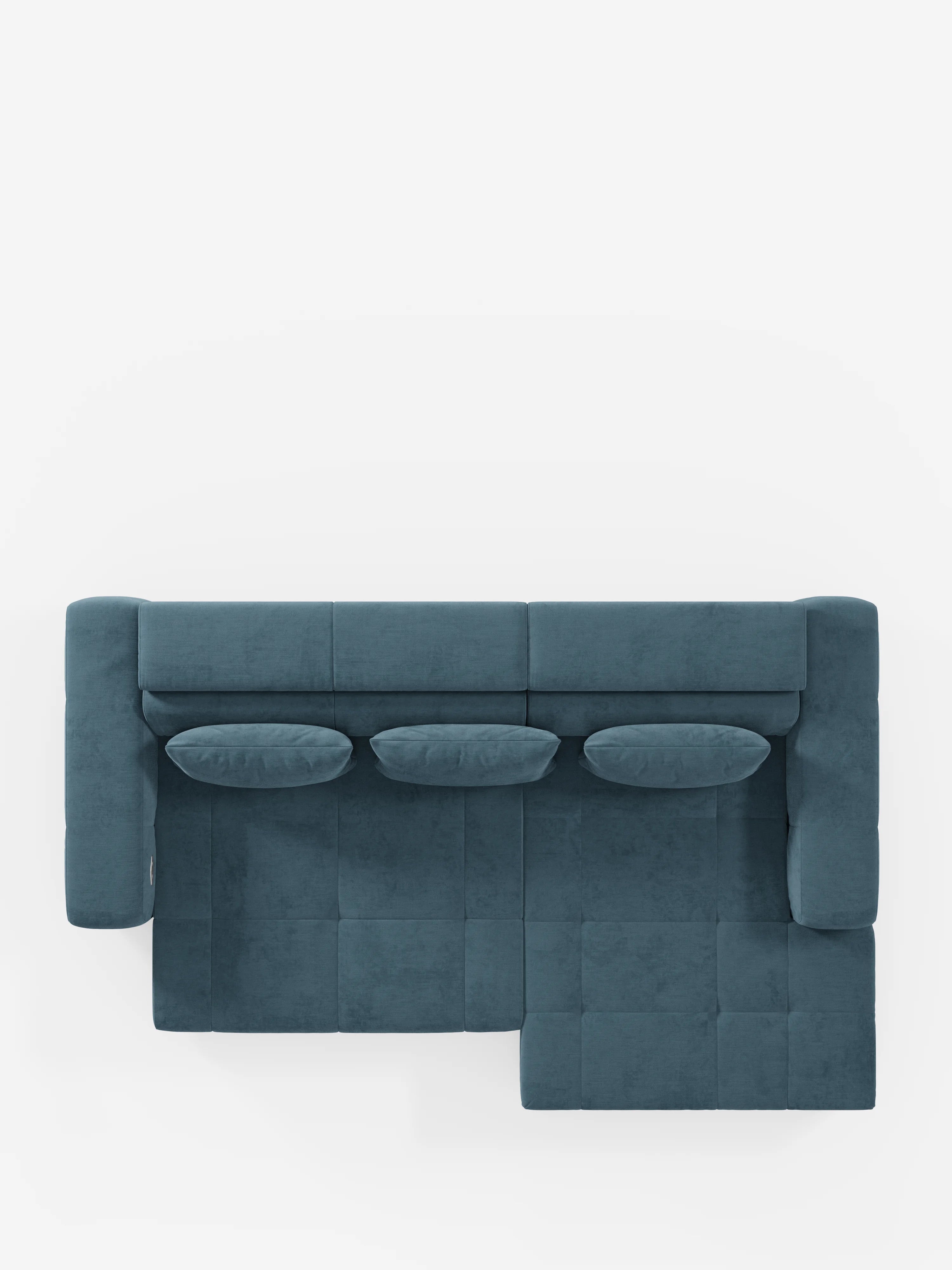 Il divano angolare Monarch blu con penisola e funzione Relax Elettrico per l'allungamento delle sedute di divitt.sbs è ripreso dall'alto e presenta tre cuscini dello schienale e tre cuscini decorativi ovali abbinati, realizzati nello stesso morbido tessuto T31 facile da pulire. Il divano, dotato di poggiatesta regolabili, è posizionato su uno sfondo bianco che ne mette in risalto le sezioni rettangolari e quadrate della seduta, oltre al design pulito e moderno.