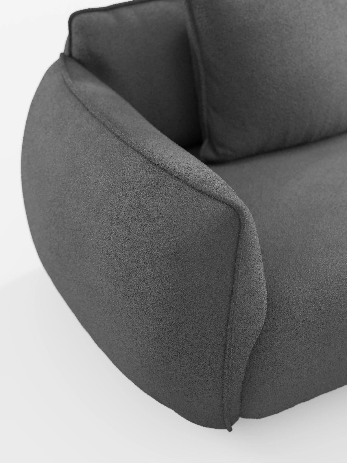 Un primo piano del divano modulare e componibile a 3 posti Nimbus da 250 cm di divitt.sbs, rivestito in tessuto T33 effetto cotone lavabile di colore grigio scuro. Il divano modulare presenta un'imbottitura morbida, bordi arrotondati, un bracciolo leggermente rialzato e una texture del tessuto soffice. È ripreso su uno sfondo bianco a tinta unita per mettere in risalto il suo design elegante e minimalista.