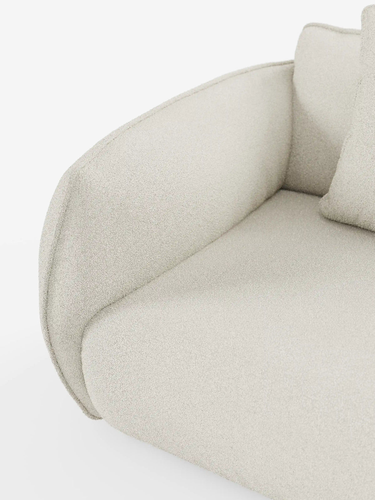 Primo piano del divano angolare con penisola componibile Nimbus di divitt.sbs, che mette in risalto i braccioli e la seduta curvi e imbottiti, rivestiti in tessuto T33 effetto cotone beige chiaro, testurizzato e resistente alle macchie. È visibile una parte di un cuscino coordinato, che mette in risalto il design minimalista del divano, caratterizzato da linee pulite e da un aspetto morbido e accogliente.