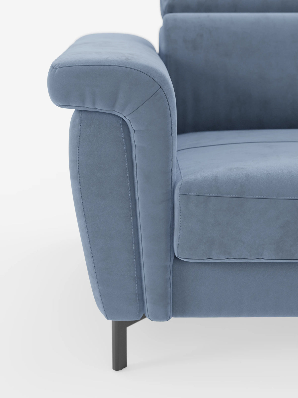 Primo piano del divano letto di design Capri di divitt.sbs, che mette in risalto i suoi moderni cuscini di seduta e braccioli in azzurro chiaro. Il raffinato tessuto effetto velluto smacchiabile T30 appare morbido, simile alla pelle scamosciata e soffice. Questo divano presenta linee pulite, un'imbottitura generosa, cuciture discrete, poggiatesta reclinabili e poggia su sottili piedini alti in metallo nero. Lo sfondo è bianco a tinta unita.