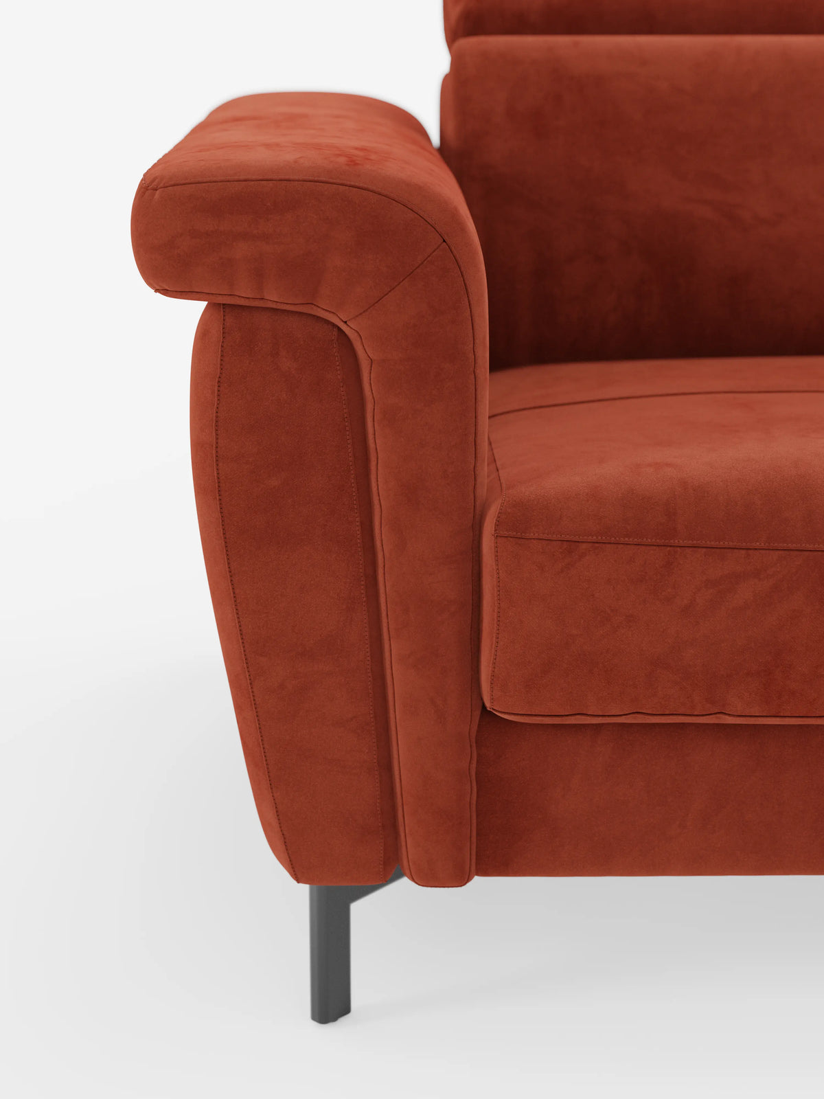 Primo piano del divano letto di design Capri di divitt.sbs, rivestito in tessuto T30 effetto velluto color ruggine e resistente alle macchie sul bracciolo sinistro, sul cuscino della seduta e sullo schienale. La poltrona presenta linee pulite e moderne con poggiatesta reclinabile e poggia su alte gambe in metallo nero su uno sfondo bianco.