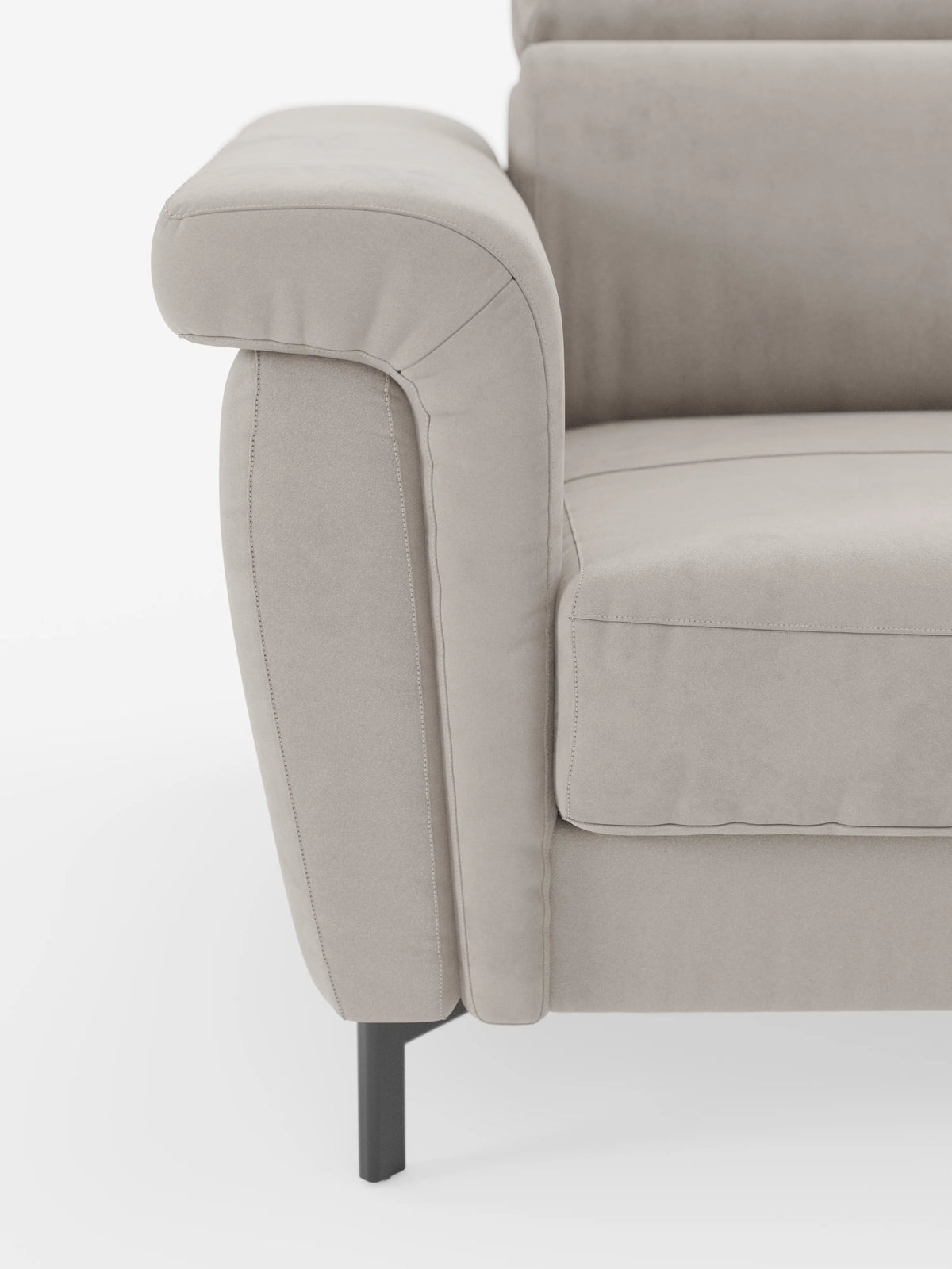 Primo piano del bracciolo sinistro e del cuscino di seduta del divano letto di design Capri con piedini alti di divitt.sbs, rivestito in un raffinato tessuto effetto velluto smacchiabile T30, morbido al tatto. Questo divano beige presenta linee pulite, cuciture a vista e poggia su eleganti gambe in metallo nero con poggiatesta regolabili: un esempio straordinario di manifattura italiana. Lo sfondo è bianco a tinta unita.