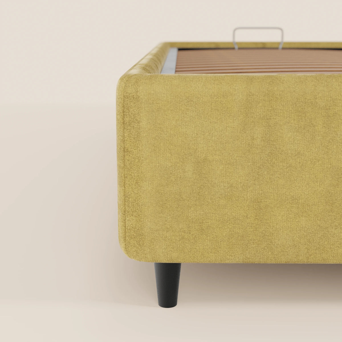 Primo piano del letto sommier imbottito con contenitore ERON di Letti.store, realizzato in tessuto impermeabile Oeko-Tex color senape. Nell'immagine sono visibili un angolo arrotondato e una gamba in legno, mentre le doghe e lo sfondo a tinta unita ne esaltano il design moderno.
