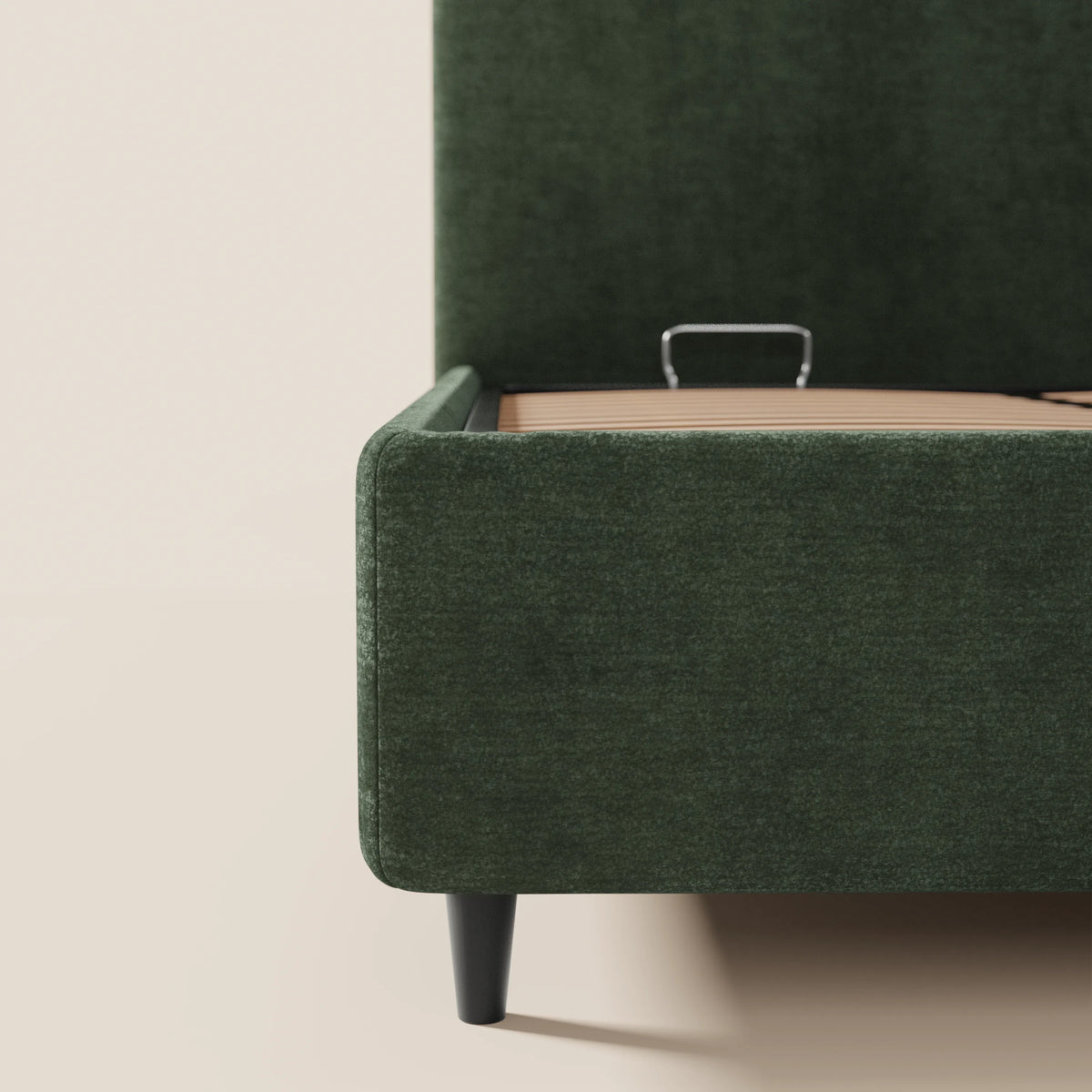 Primo piano del letto imbottito KAELOS minimal di Letti.store, realizzato in tessuto chiné verde scuro, caratterizzato da gambe alte nere, testiera arrotondata e vano contenitore. Design moderno con sponde laterali e pediera a vista e supporto centrale in metallo per il materasso su una base chiara.