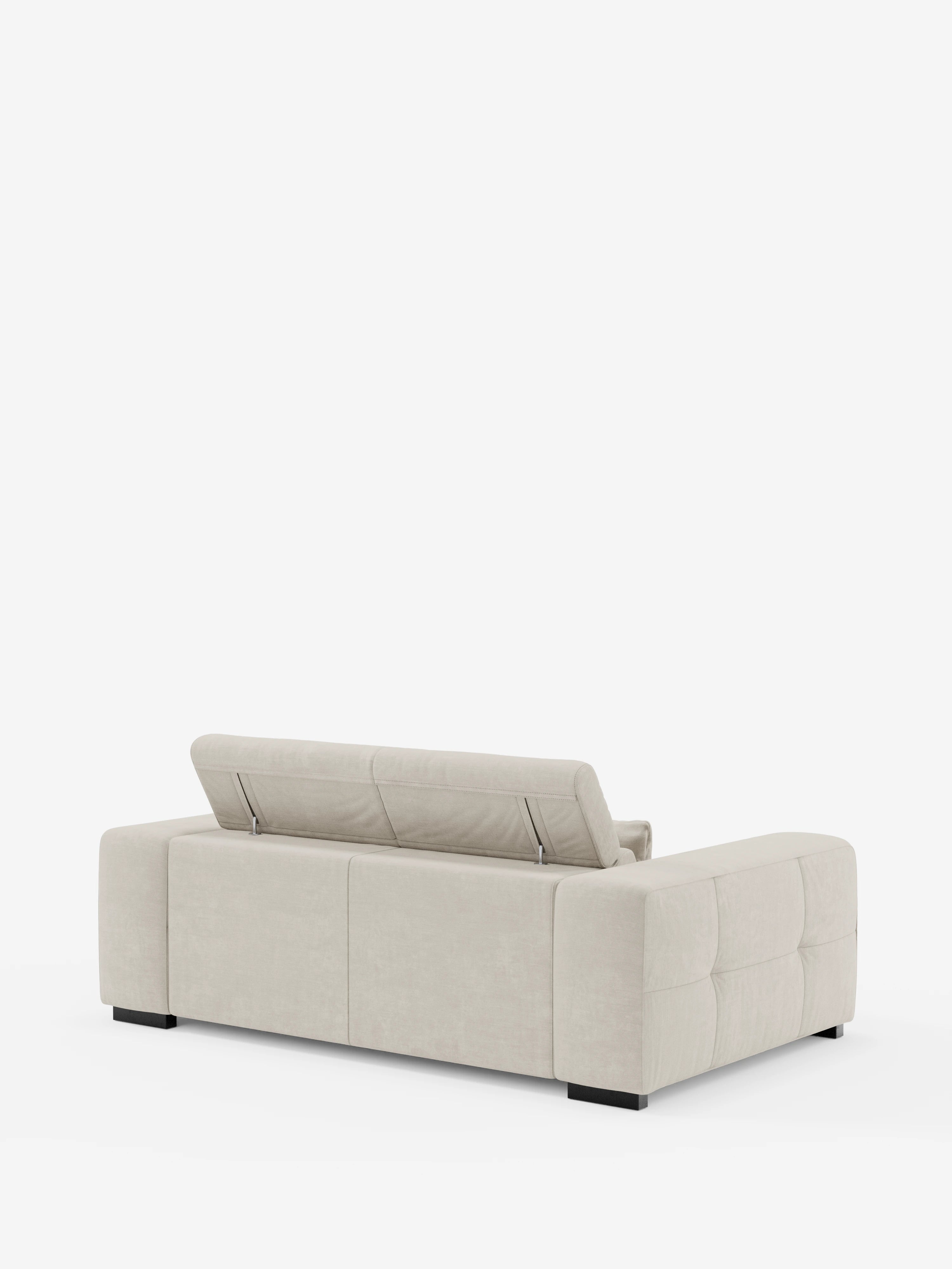Il divano contemporaneo Monarch con funzione relax elettrica per l'allungamento delle sedute e poggiatesta reclinabile, realizzato in morbido tessuto smacchiabile T31 da divitt.sbs, in una tonalità beige chiaro, presenta una silhouette squadrata e morbidi braccioli trapuntati. Il divano presenta angoli squadrati, poggiatesta regolabili parzialmente rialzati sullo schienale e poggia su bassi piedini neri su uno sfondo bianco.