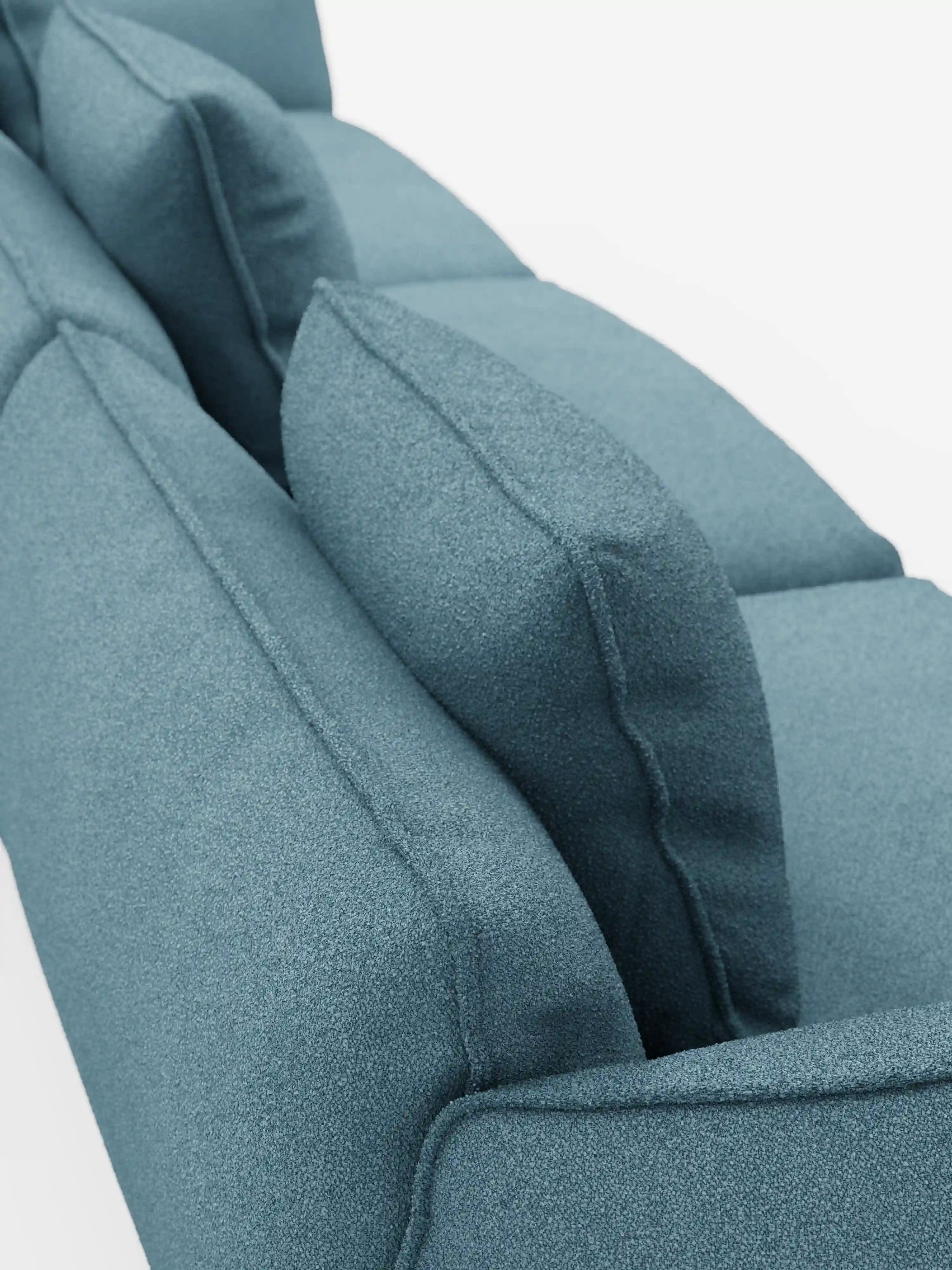 Un primo piano del divano modulare a 3 posti Nimbus, realizzabile in morbido tessuto smacchiabile effetto cotone T33 di divitt.sbs, che mette in risalto il rivestimento in tonalità verde acqua con texture, lo schienale e i cuscini angolari dello schienale su uno sfondo bianco. Questo divano moderno è caratterizzato da cuscini eleganti e morbidi che ne sottolineano il design contemporaneo e l’imbottitura confortevole.