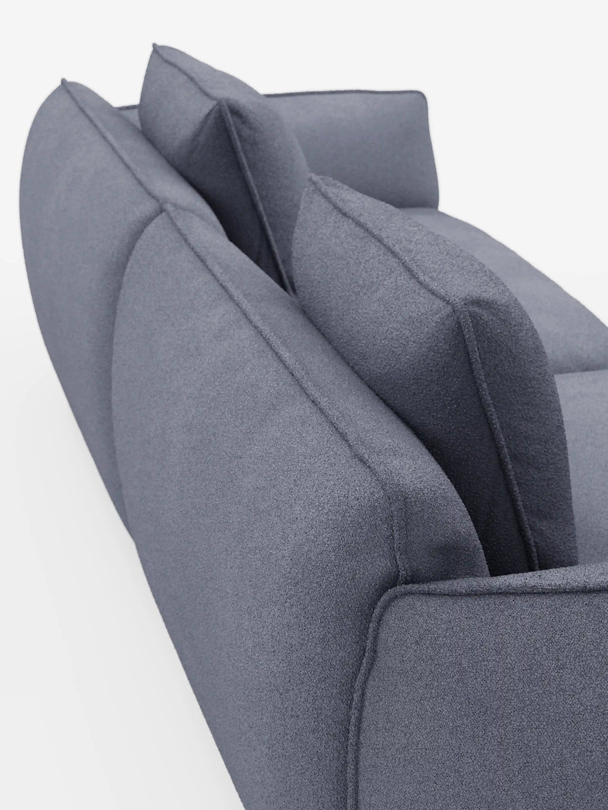 Primo piano della parte posteriore del divano modulare e componibile a 3 posti Nimbus di divitt.sbs, lungo 250 cm, rivestito in tessuto sfoderabile e antimacchia effetto cotone t33 in grigio moderno, dotato di due cuscini dello schienale e due ampi cuscini di seduta. Su uno sfondo bianco a tinta unita, l’immagine mette in risalto la morbida trama del tessuto e le linee pulite e scolpite del divano.
