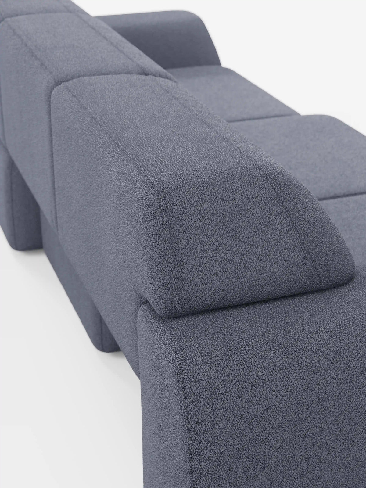 Un divano Orbit minimalista e contemporaneo in tessuto grigio, con 3 sedute scorrevoli e allungabili in tessuto effetto cotone smacchiabile T33 di divitt.sbs, caratterizzato da schienali e braccioli dalla forma geometrica massiccia. Il rivestimento presenta una delicata trama in rilievo ed è completamente sfoderabile per una facile manutenzione. Ripreso da un'angolazione laterale posteriore su sfondo bianco, questo modello offre uno stile moderno unito a una funzionalità pratica.