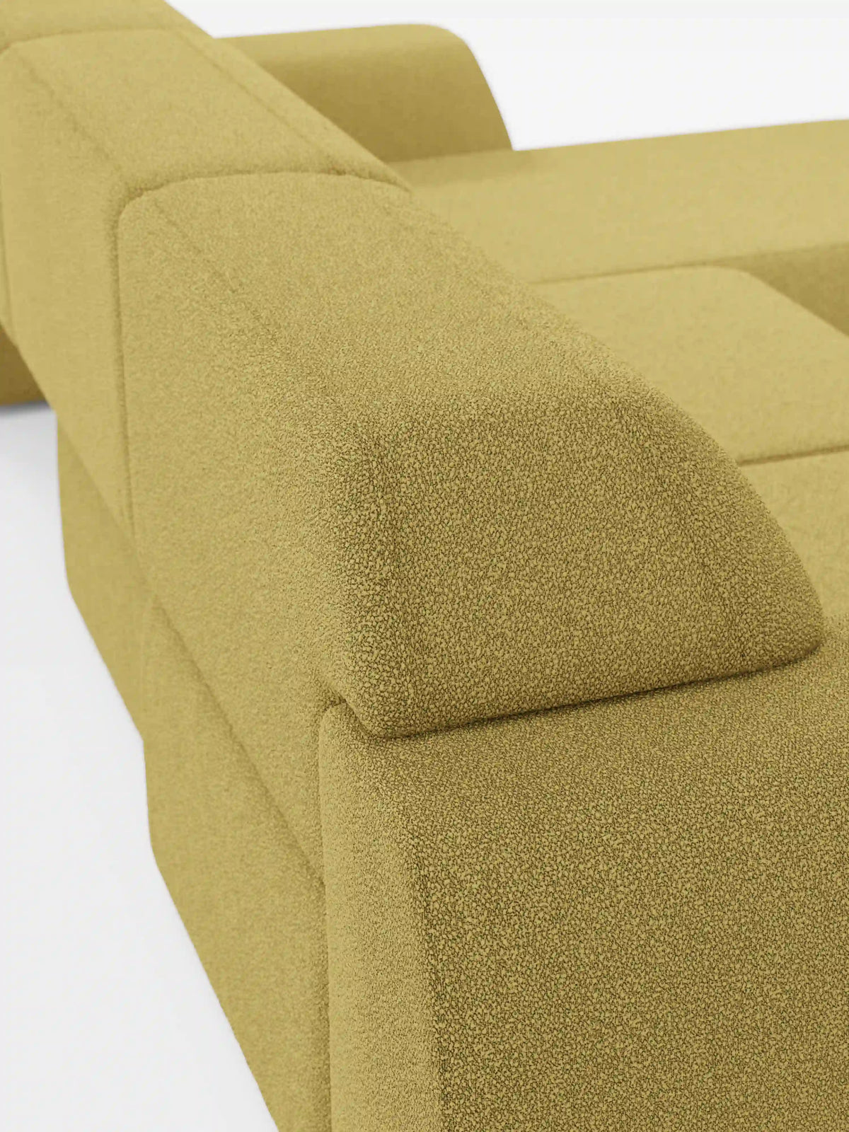 Primo piano del divano angolare Orbit con penisola reversibile e tutte le sedute allungabili di divitt.sbs, rivestito in tessuto T33 testurizzato effetto cotone, resistente alle macchie, in giallo senape. L’immagine mette in risalto il bracciolo e la parte superiore dello schienale, caratterizzati da linee geometriche pulite su uno sfondo bianco a tinta unita. Il divano si caratterizza per un aspetto morbido e imbottito e uno stile minimalista.