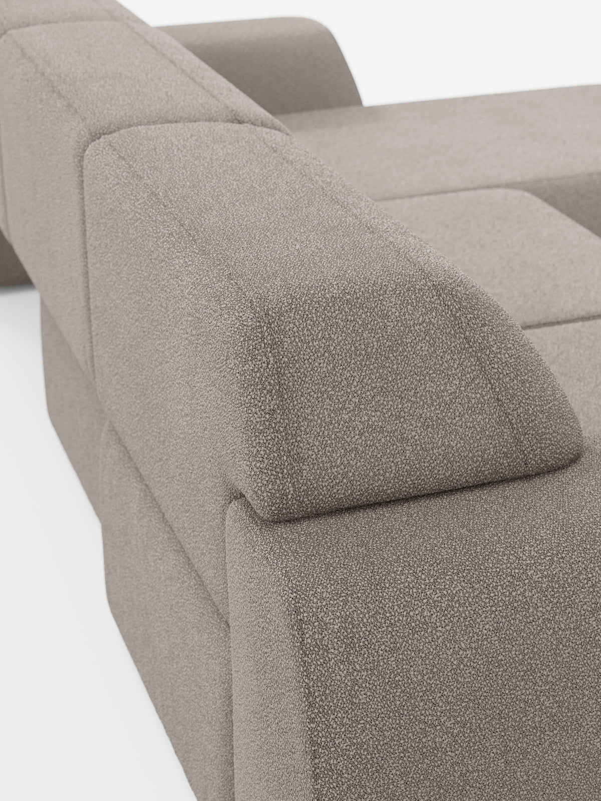 Primo piano del divano angolare Orbit con penisola reversibile e tutte le sedute allungabili di divitt.sbs, rivestito in tessuto T33 effetto cotone grigio chiaro, resistente alle macchie. Questo moderno divano componibile si caratterizza per le forme geometriche a blocchi e gli ampi braccioli. L’immagine mette in risalto il bracciolo e lo schienale, sottolineando la consistenza morbida, le linee pulite e raffinate e il design contemporaneo di questo pezzo di alta gamma.