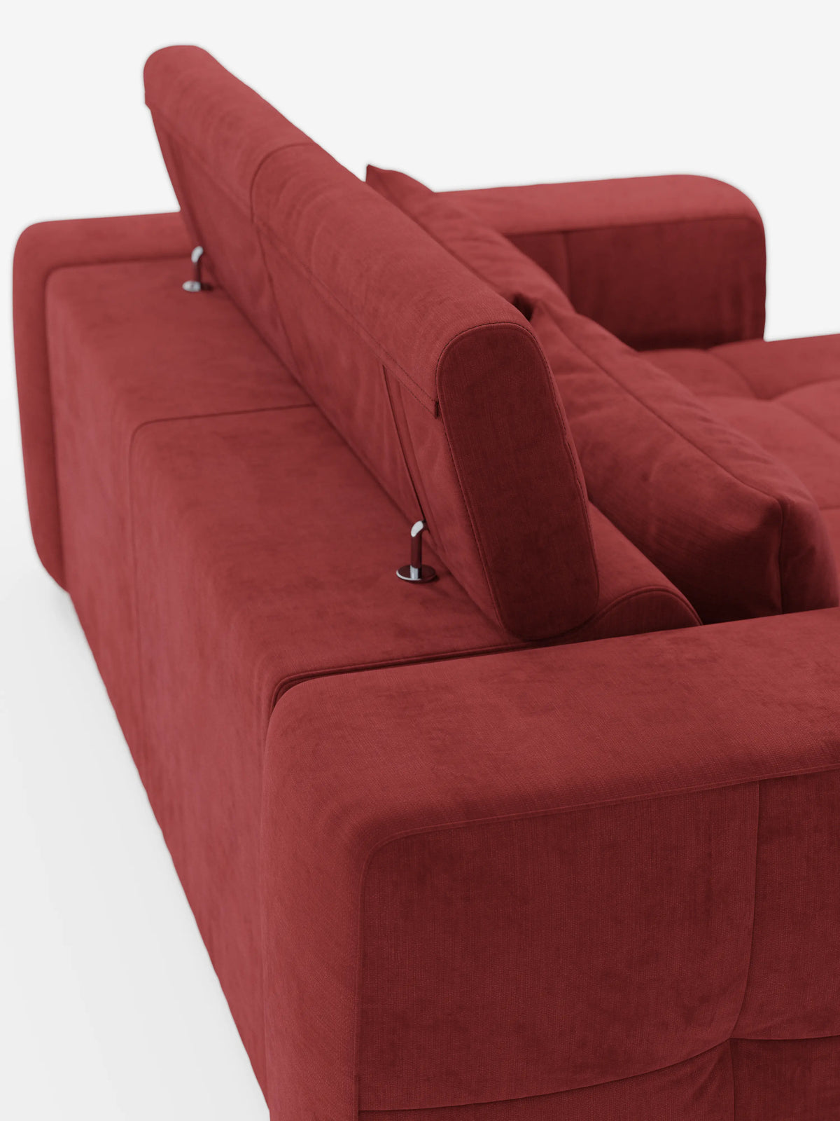 Un divano contemporaneo rosso “Monarch” con funzione relax elettrica per l’allungamento delle sedute e poggiatesta reclinabile in morbido tessuto lavabile T31 di divitt.sbs è ripreso di spalle da un’angolazione obliqua. Il poggiatesta in posizione verticale, sostenuto da eleganti cerniere in metallo, e i cuscini morbidi e soffici evocano una sensazione di comfort che ricorda quella di un classico divano relax elettrico. L’ambientazione minimalista è caratterizzata da uno sfondo bianco brillante.