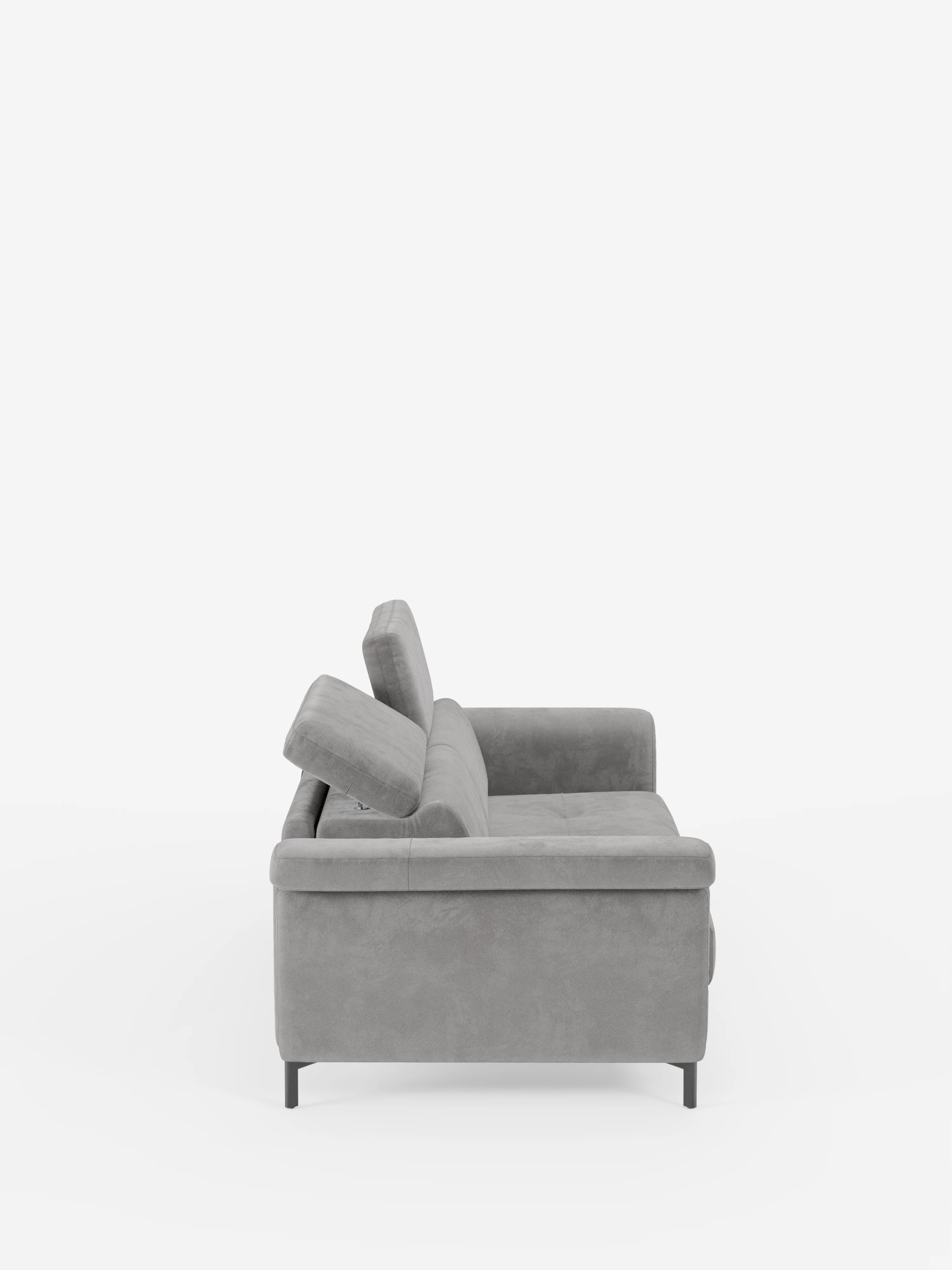 Vista laterale del divano letto di design Capri di divitt.sbs, caratterizzato da un raffinato tessuto T30 effetto velluto grigio antimacchia, sottili gambe alte in metallo nero, schienali angolati con poggiatesta reclinabili, una seduta morbida e braccioli dritti, il tutto su uno sfondo bianco a tinta unita.