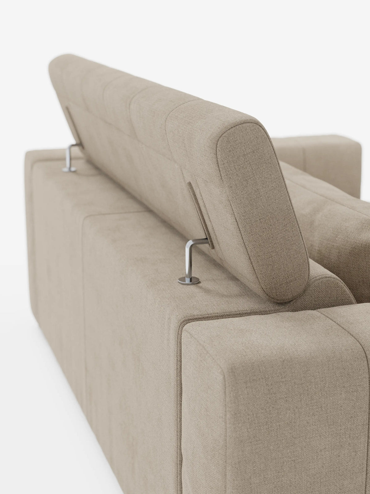 Il divano a 3 posti Doric di divitt.sbs è ripreso di retro su uno sfondo bianco liscio, mettendo in risalto il suo design contemporaneo in tessuto T23 beige antimacchia. Il poggiatesta sinistro rimane in posizione verticale mentre quello destro è reclinato; entrambi sono sostenuti da eleganti aste metalliche che ne sottolineano la regolabilità, mettendo in evidenza la versatilità del modello grazie al sistema «relax elettrico» e ai poggiatesta reclinabili.