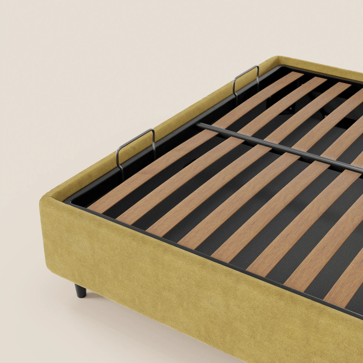 Un primo piano del letto sommier imbottito ERON di Letti.store mostra la sua base in tessuto impermeabile Oeko-Tex color giallo senape, i supporti in metallo nero, le doghe in legno e due barre verticali interne. Lo sfondo è di colore crema a tinta unita.
