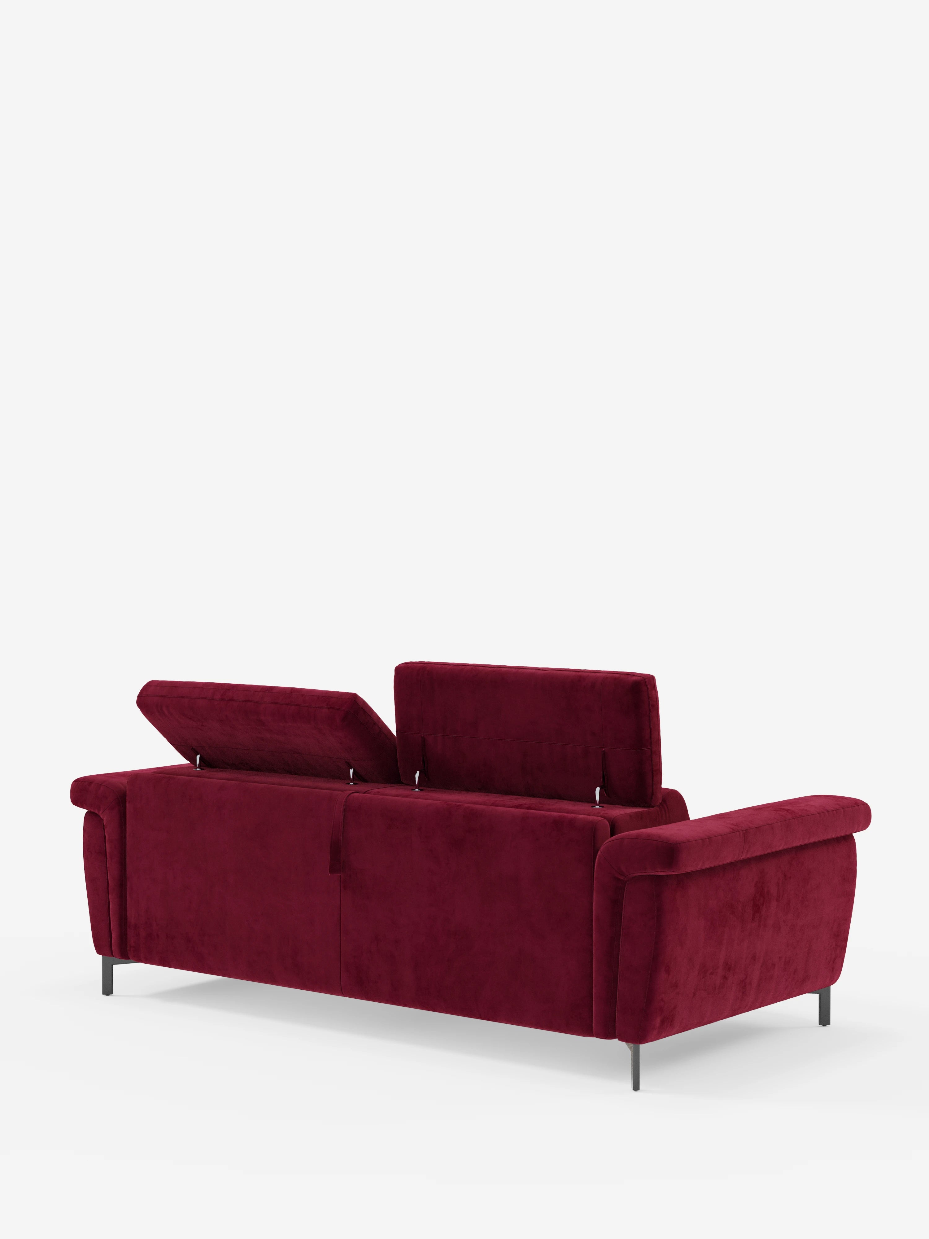 Un moderno divano letto di design Capri di divitt.sbs, rivestito in raffinato tessuto T30 effetto velluto, resistente alle macchie, in un rosso intenso. Il divano presenta due pannelli posteriori ribaltabili che rivelano uno spazio contenitivo nascosto e include braccioli bassi e larghi con eleganti gambe alte di colore nero. I poggiatesta reclinabili aggiungono comfort e stile, il tutto su uno sfondo bianco a tinta unita.