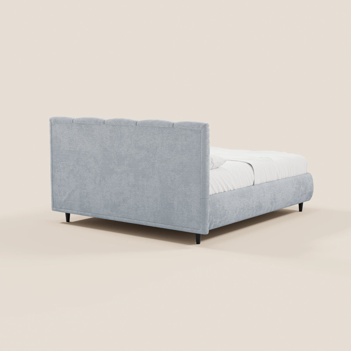 Il letto imbottito ARKAM di Letti.store, dotato di vano contenitore e testiera con lavorazione verticale in tessuto certificato Oeko-Tex®, si distingue per il suo design shabby chic e le linee pulite. Immagine che ne mostra la parte posteriore su uno sfondo beige chiaro, con gambe basse nere e biancheria da letto bianca.