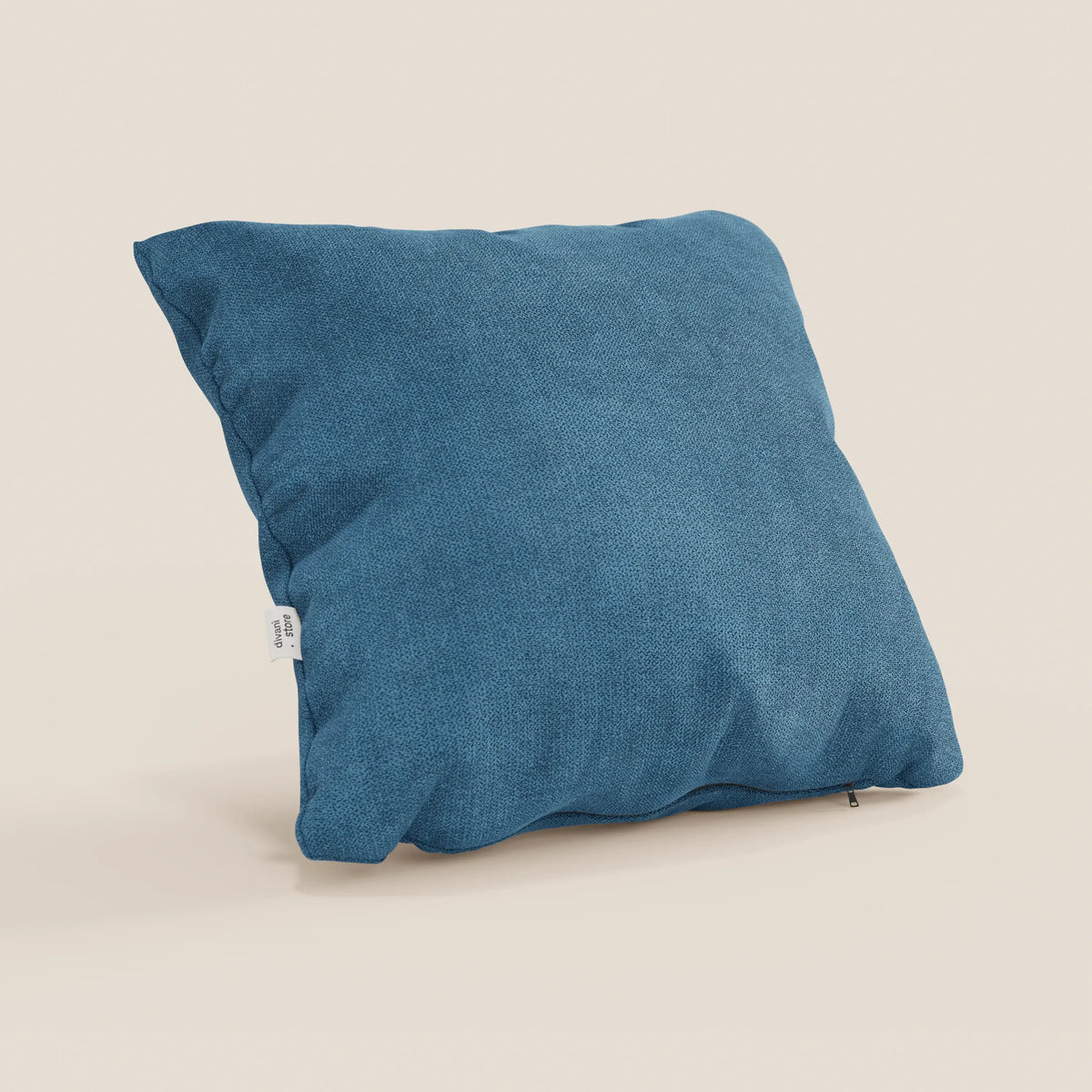 Il cuscino Destiny di divitt.sbs, 45x45 cm in morbido tessuto impermeabile T02 azzurro, si erge su uno sfondo beige chiaro. Una piccola etichetta bianca è applicata su un lato e una cerniera parzialmente visibile corre lungo il bordo inferiore.