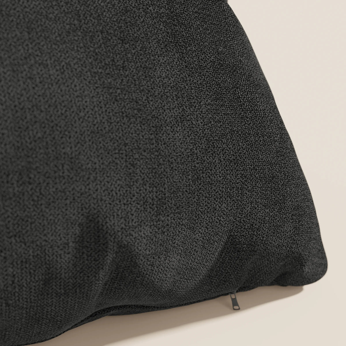 Primo piano del cuscino Destiny 45x45 cm di divitt.sbs in tessuto morbido impermeabile T02 nero, con una sottile trama intrecciata e rivestimento lavabile. Il cuscino appare morbido con una cerniera visibile su una superficie chiara.