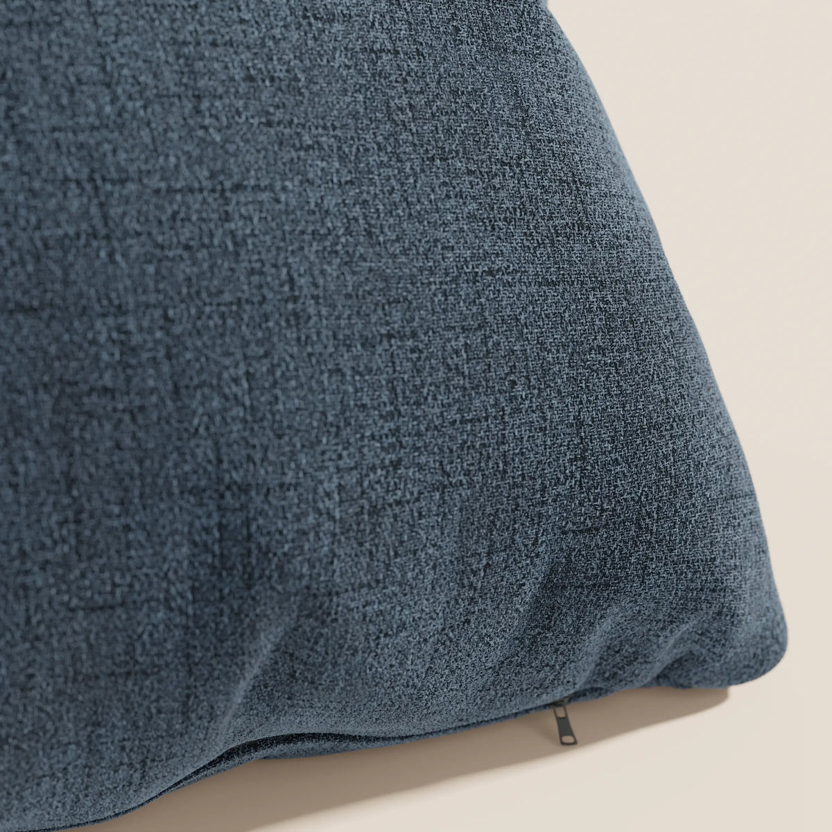 Primo piano del cuscino impermeabile Felis T03 blu di divitt.sbs, caratterizzato da una superficie morbida e intrecciata con un sottile motivo a griglia e una cerniera parzialmente visibile, su uno sfondo beige chiaro.