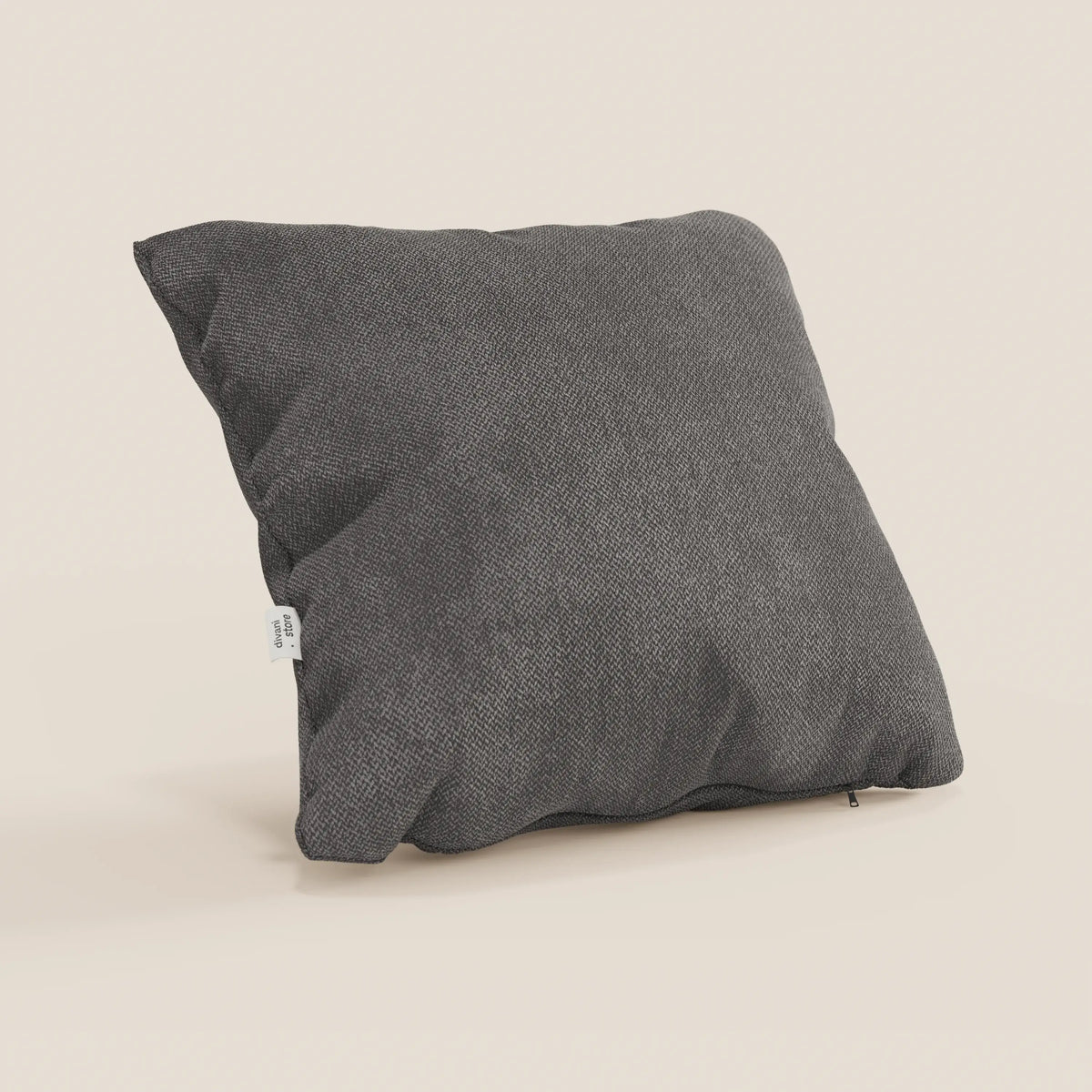 Il cuscino Sogno di divitt.sbs, qui presentato nel colore SMACCHIABILE T05 antracite, presenta un design quadrato grigio scuro con morbido tessuto antimacchia, una targhetta bianca sul lato sinistro e una cerniera inferiore parzialmente visibile su sfondo beige.