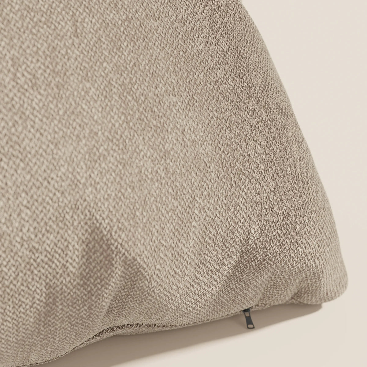 Primo piano del cuscino Sogno di divitt.sbs in tessuto morbido smacchiabile T05 beige, caratterizzato da un raffinato motivo a intreccio e da una piccola cerniera nera all'angolo, ideale per cuscini eleganti.