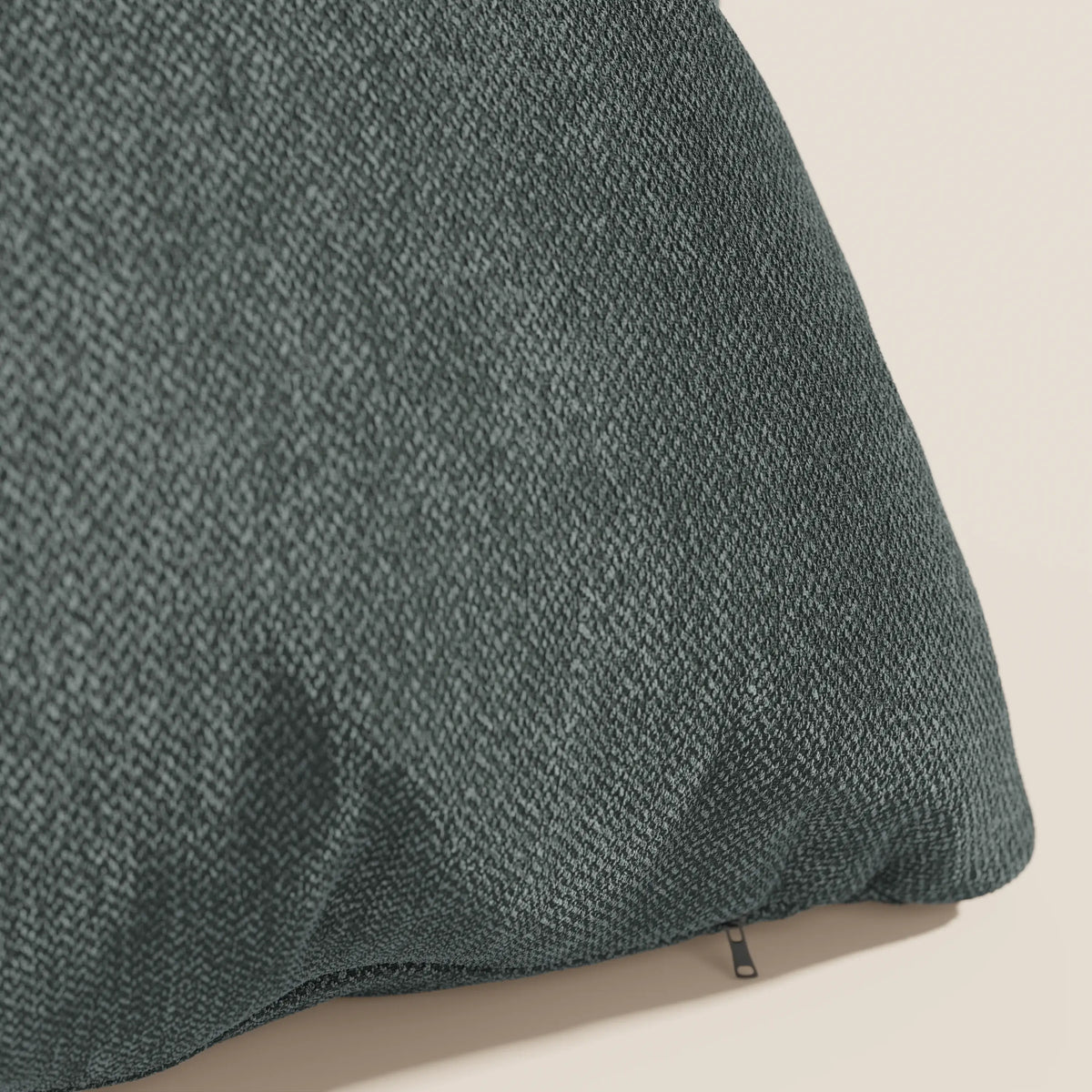 Primo piano del cuscino Sogno cuscino di divitt.sbs in SMACCHIABILE T05 verde: un cuscino verde scuro, dalla texture morbida, con un sottile disegno a spina di pesce e una discreta cerniera, mostrato su uno sfondo beige chiaro. Disponibile in vari colori.