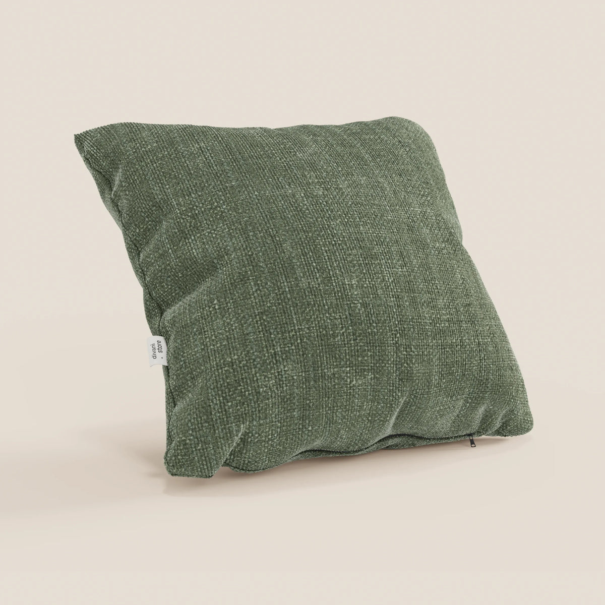 Il cuscino Lyon 45x45 T06 verde di divitt.sbs, in morbido tessuto impermeabile, si erge su uno sfondo beige chiaro. Su un lato è presente una targhetta bianca con testo e la cerniera inferiore è parzialmente aperta.