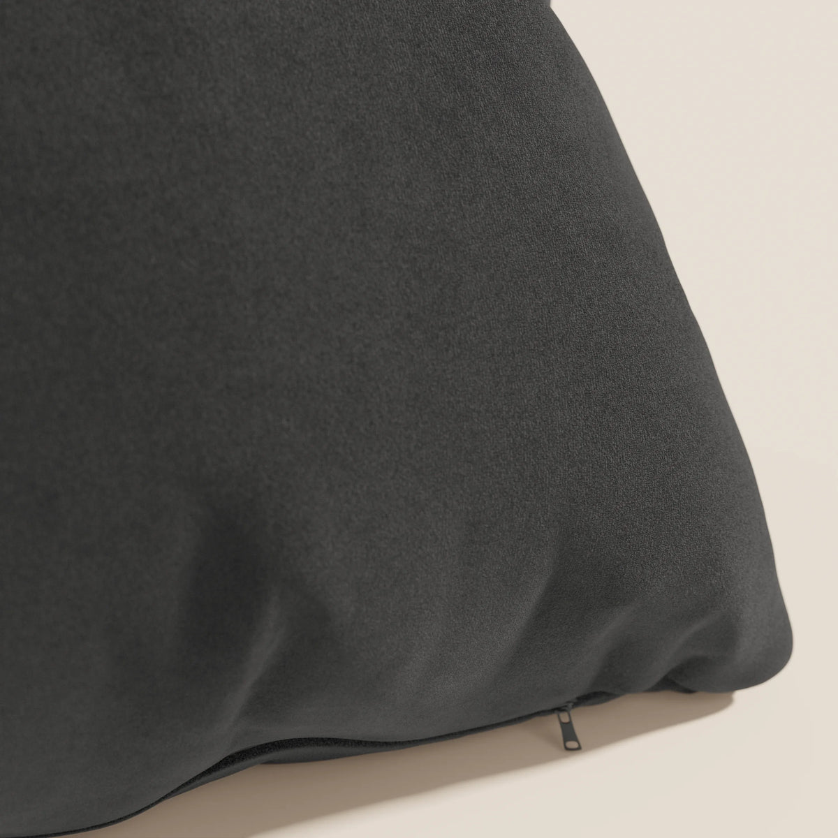 Primo piano del cuscino Jazz di divitt.sbs in nero T11, realizzato in microfibra tecnica antimacchia. Il cuscino è caratterizzato da una texture sottile, è sfoderabile con cerniera nascosta ed è inserito in un semplice sfondo beige chiaro.
