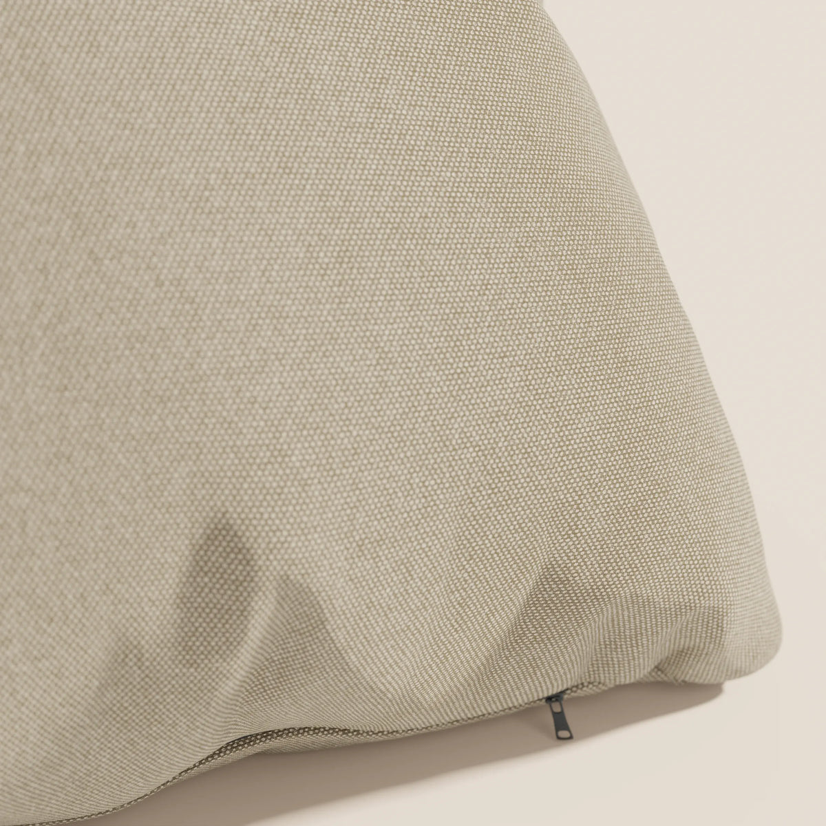 Primo piano del cuscino Honey di divitt.sbs, in tessuto simil cotone impermeabile T13 beige, dimensioni 45x45. Le pieghe sottili e la cerniera nera aggiungono dettagli al suo aspetto fine e intrecciato su uno sfondo chiaro.