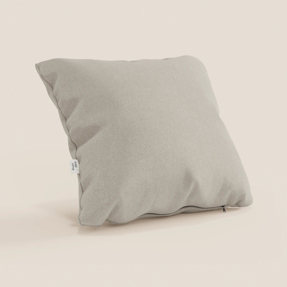 Il cuscino Honey grigio chiaro 45x45 cm di divitt.sbs è posizionato in verticale su uno sfondo neutro. Realizzato in tessuto impermeabile simil cotone T13 panna, presenta una cucitura a vista, una piccola etichetta bianca, una cerniera e una fodera lavabile per una facile manutenzione.
