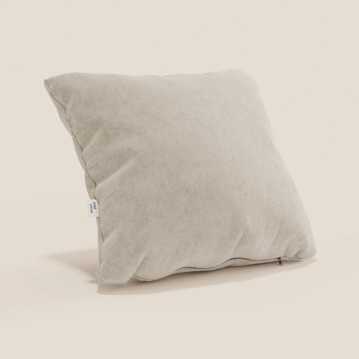 Il cuscino Bolero di divitt.sbs, qui presentato in tessuto T31 beige chiaro, è leggermente abbondante, con etichetta bianca visibile e cerniera scura. Il morbido rivestimento, antimacchia, impermeabile e non restringente, poggia in posizione obliqua su un fondo bianco sporco.
