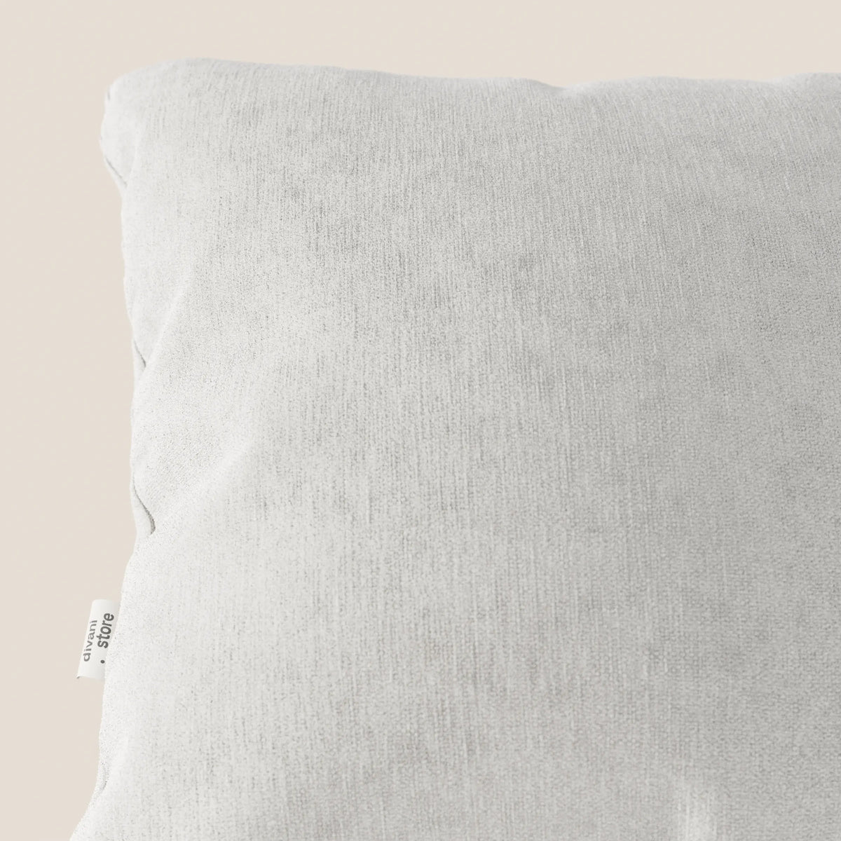 Primo piano del cuscino Bolero di divitt.sbs, nel colore grigio chiaro con una texture sottile. Realizzato in morbido tessuto T31, resistente alle macchie, impermeabile e non restringibile. Una piccola etichetta bianca appare sul bordo sinistro su uno sfondo beige.