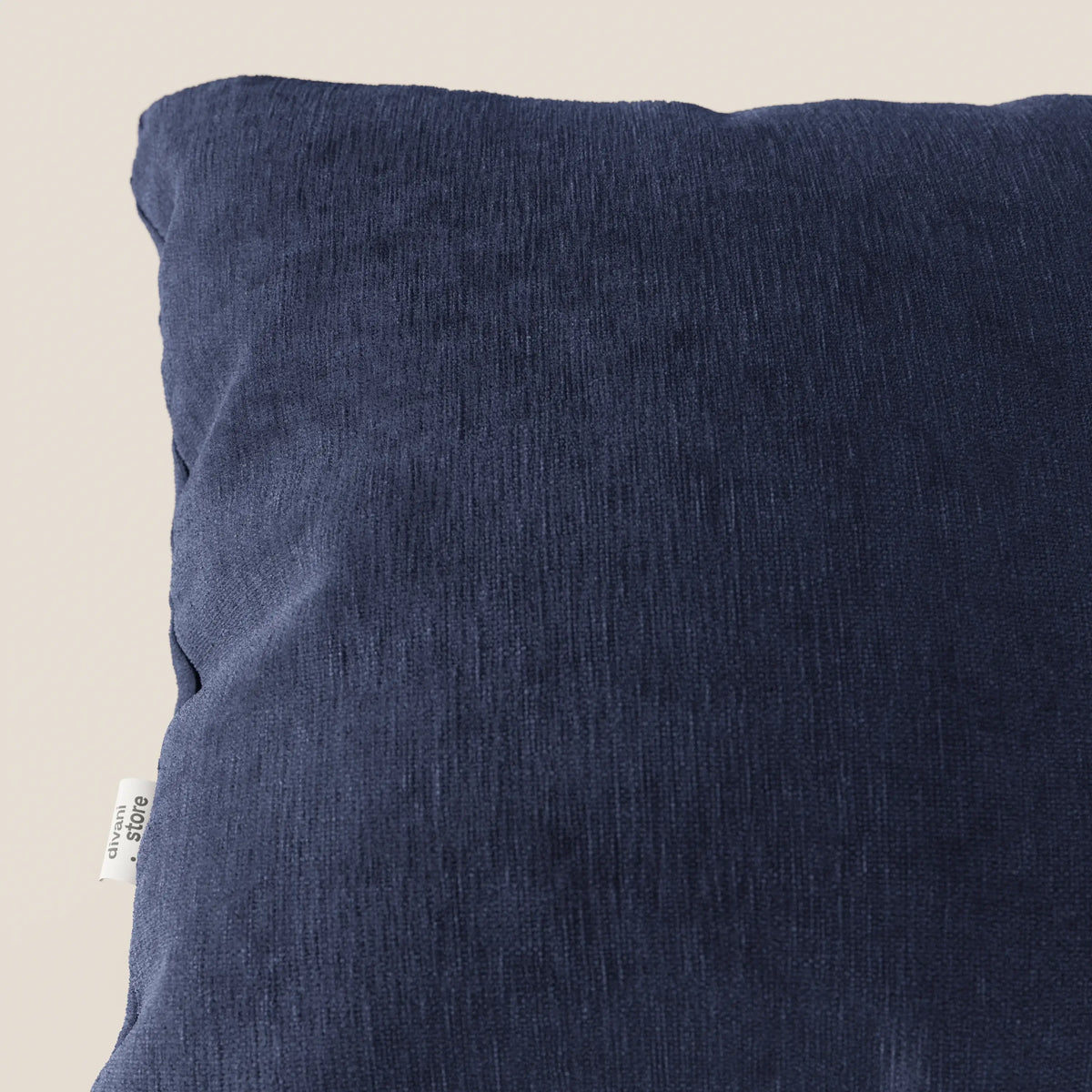 Primo piano del cuscino Bolero di divitt.sbs in blu navy, realizzato in morbido tessuto T31 antimacchia, impermeabile e non restringente. Il cuscino presenta leggere rughe e una piccola etichetta bianca; lo sfondo è chiaro e neutro.
