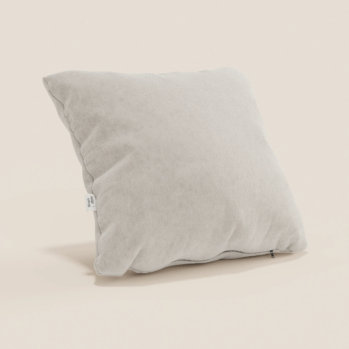 Un cuscino Bolero grigio chiaro di divitt.sbs, quadrato e leggermente gonfio con una sottile texture, poggia ad angolo su uno sfondo beige. Presenta una piccola etichetta in tessuto bianco e una cerniera lungo il bordo inferiore. Realizzato in tessuto T31 lavabile e impermeabile.