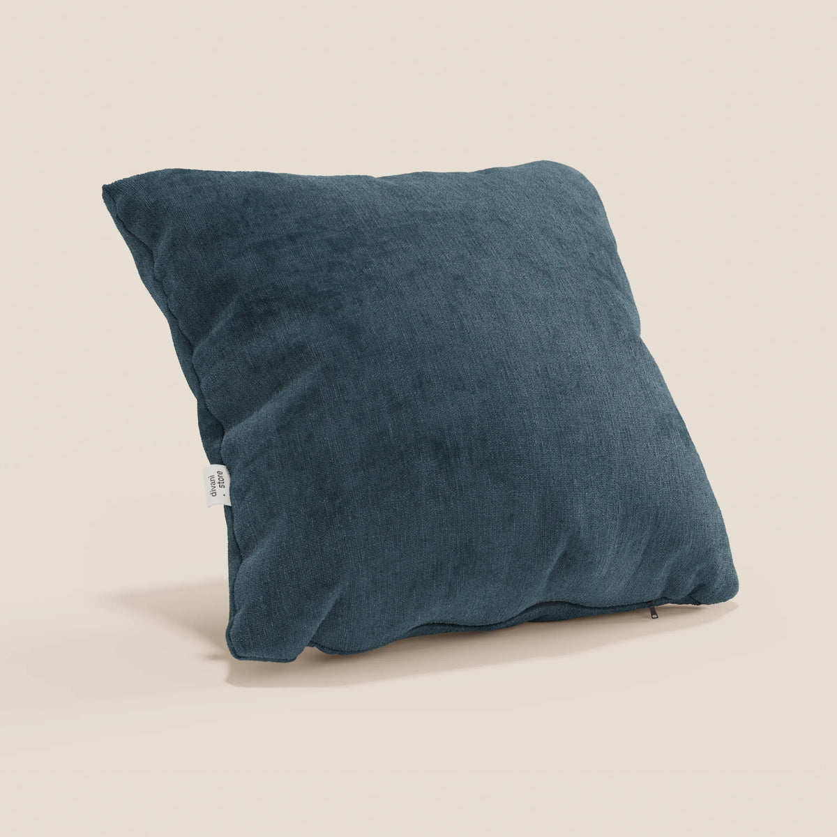 Un cuscino Bolero di divitt.sbs in blu scuro, realizzato in morbido tessuto T31 antimacchia, impermeabile e non restringente, è appoggiato su una superficie beige chiaro con etichetta laterale visibile e aspetto felpato.