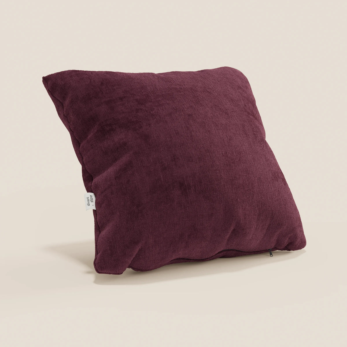 Un cuscino Bolero quadrato di colore marrone intenso di divitt.sbs poggia su una superficie beige chiaro; realizzato in morbido tessuto T31 antimacchia, impermeabile e non restringente, presenta un'etichetta laterale, lievi rughe e una piccola cerniera nell'angolo in basso a destra.
