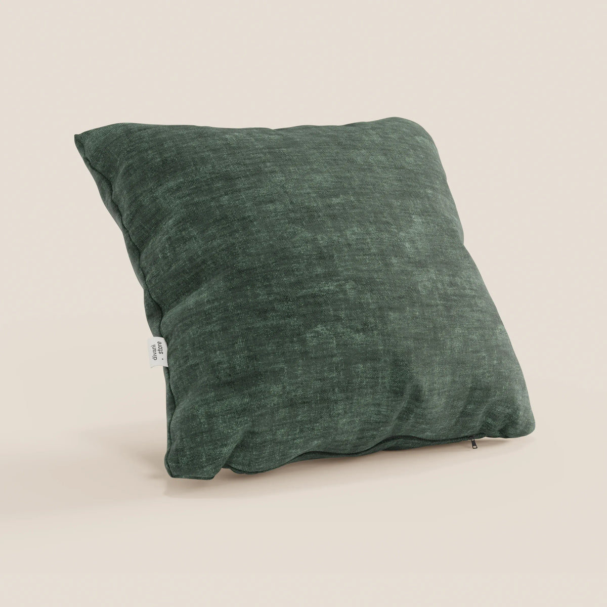 Un cuscino quadrato Sofia verde scuro di divitt.sbs, in morbido velluto nuvolato antimacchia e impermeabile (Easy Clean T35), si trova in posizione verticale su uno sfondo beige chiaro. Sono visibili anche una piccola etichetta laterale bianca e una cerniera inferiore.