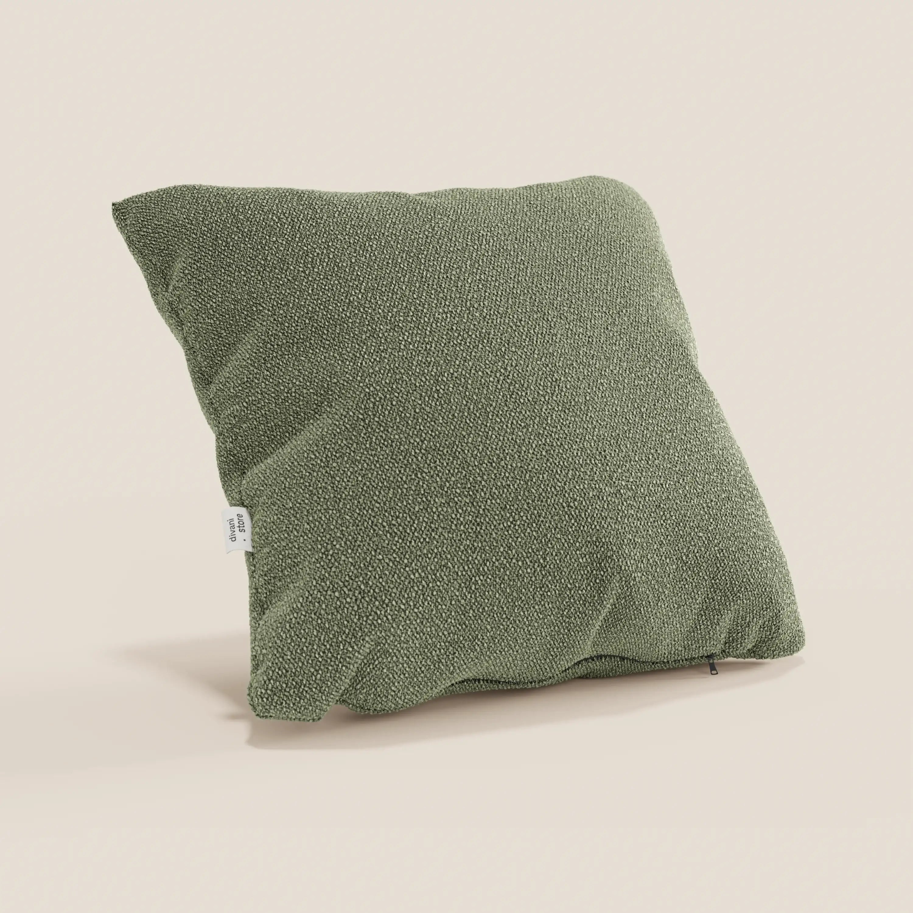 Il cuscino Lambada di divitt.sbs, presentato in un tenue verde oliva su sfondo beige, presenta un design strutturato e squadrato in tessuto lavabile e impermeabile che imita il cotone naturale, con una targhetta laterale e delicate ombre che ne accentuano l'aspetto felpato.