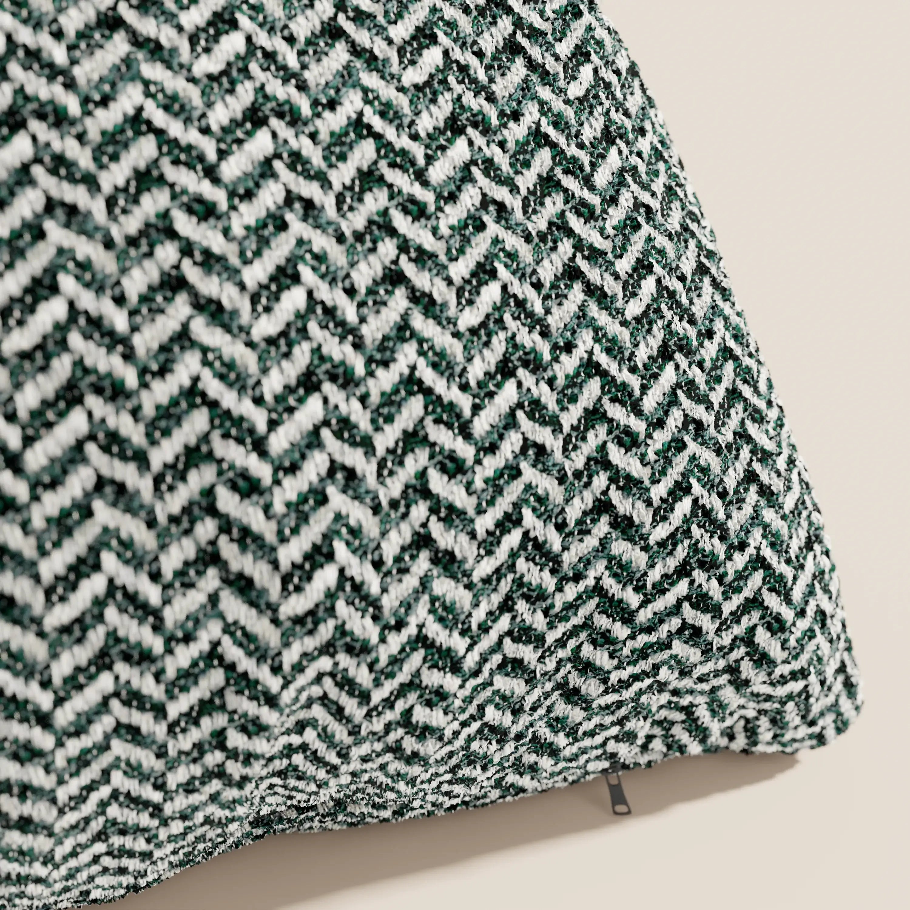 Primo piano del modello "Cuscino 45x45 in Lino" della linea Sorrento di divitt.sbs, caratterizzato da un tessuto a motivo chevron verde e bianco, una cerniera discreta che ne facilita la rimozione e fodere lavabili in lavatrice, il tutto su uno sfondo beige neutro.