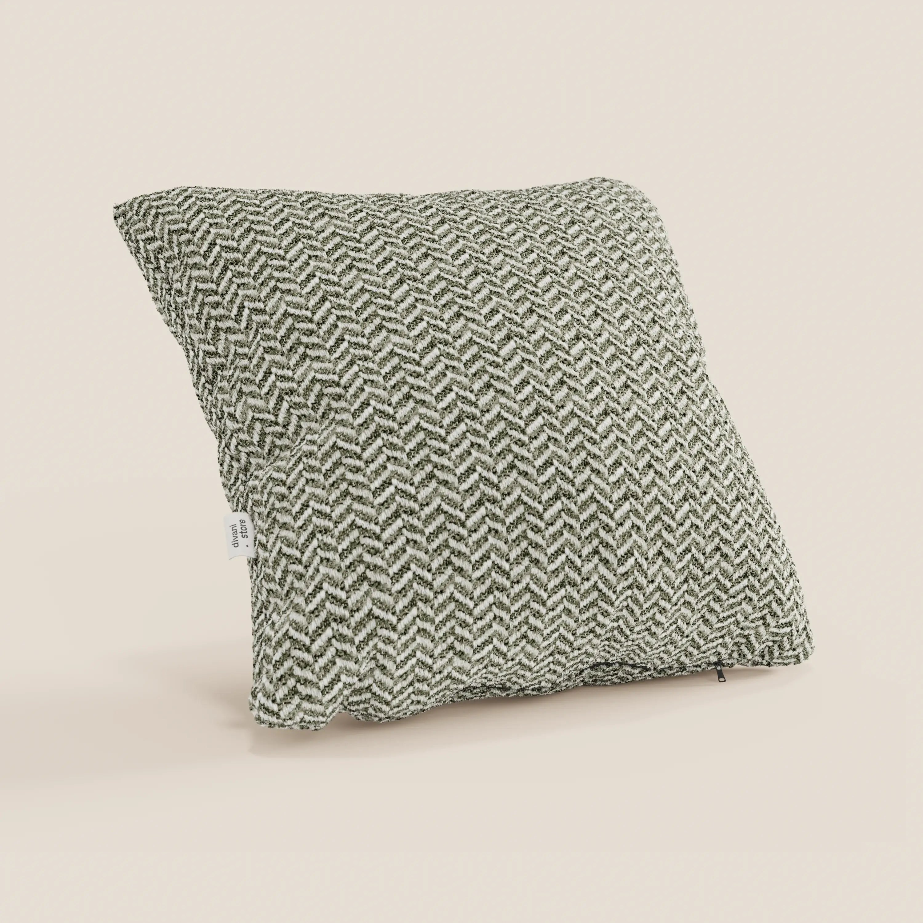 Il cuscino Sorrento 45x45 in lino | Eleganza Naturale di divitt.sbs presenta un motivo a spina di pesce in rilievo nei toni del verde scuro e del bianco sporco, ripreso di sbieco con l'etichetta del tessuto su uno sfondo beige chiaro a tinta unita.
