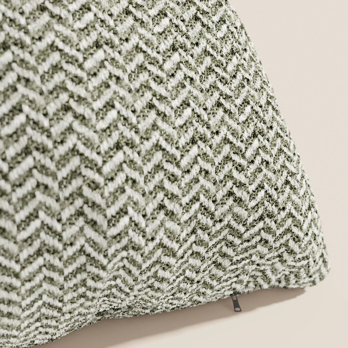 Un primo piano del cuscino Sorrento 45x45 in lino di divitt.sbs ne mette in risalto la trama a spina di pesce verde e bianca, lo sfondo beige chiaro e la piccola cerniera scura: l'ideale per chi cerca cuscini lavabili in lavatrice.