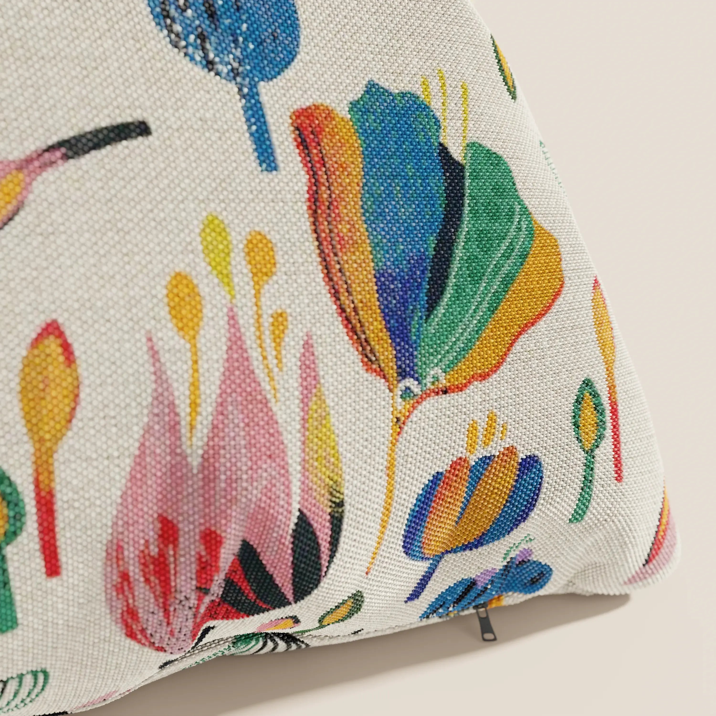 Un primo piano del cuscino Joy 45x45 cm di divitt.sbs, della collezione a fantasie multicolor in tessuto fresco cotone impermeabile panna, mostra audaci motivi floreali astratti e una cerniera visibile sul coperchio lavabile.