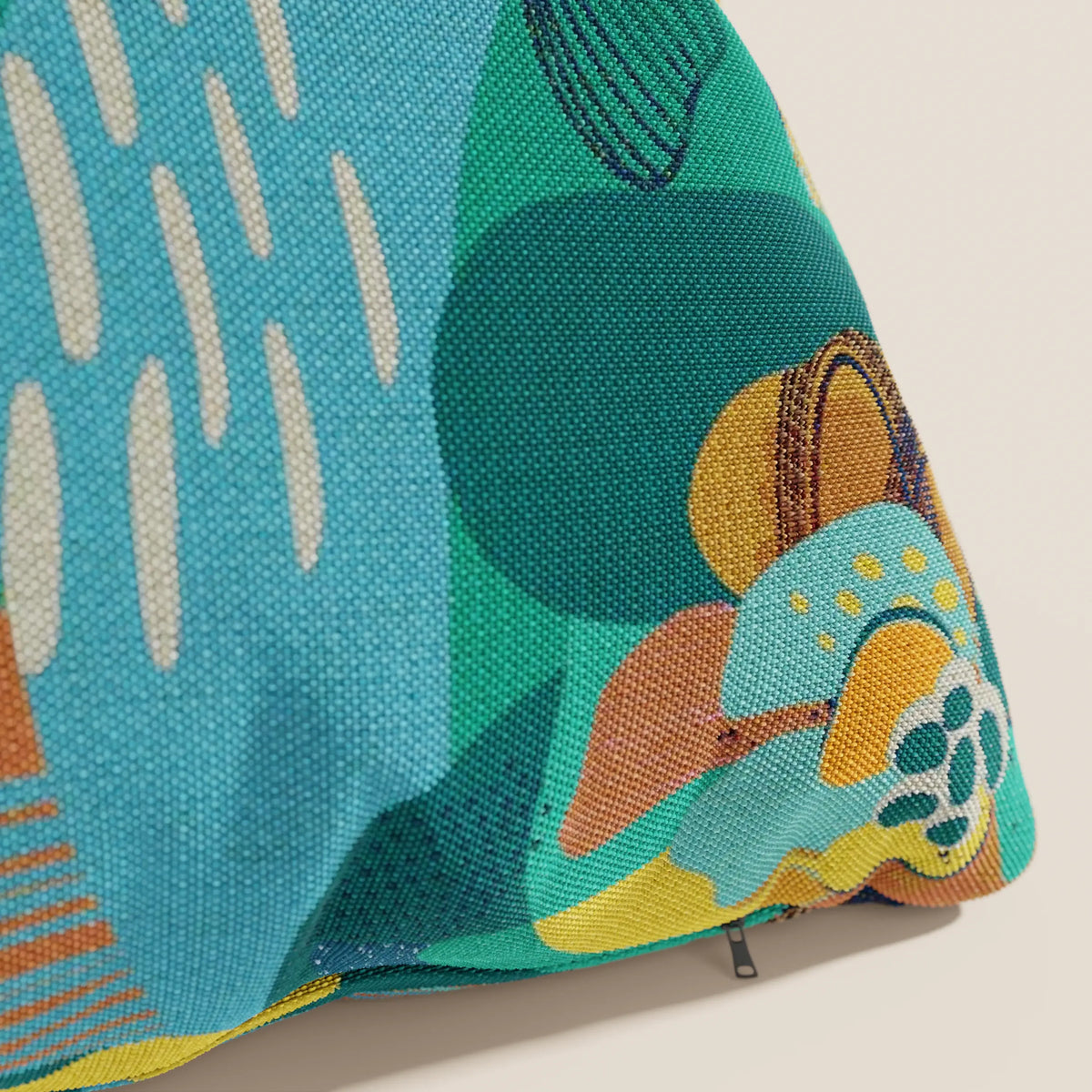 Primo piano del cuscino della collezione Joy di divitt.sbs: un cuscino astratto multicolore in fresco tessuto di cotone verde acqua, resistente all'acqua, con fodera resistente e cerniera a vista sul bordo inferiore destro. Lavabile in lavatrice.