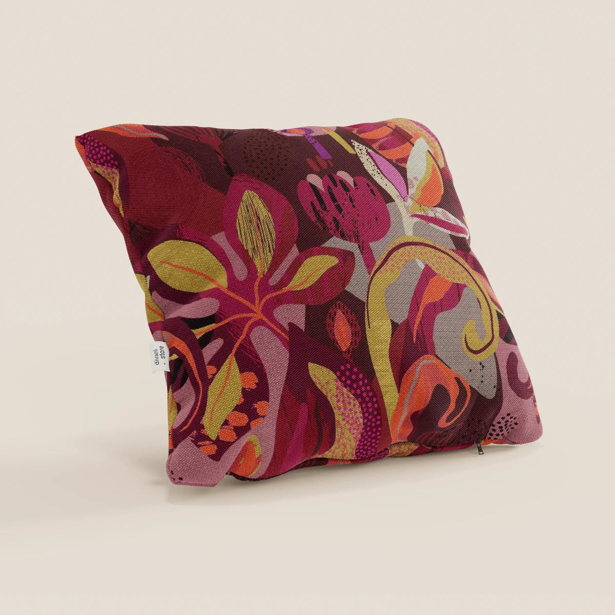 Il cuscino Joy di divitt.sbs è un cuscino quadrato di 45x45 cm in fresco cotone rosso impermeabile con un vivace motivo floreale astratto multicolore e una piccola etichetta laterale bianca, su sfondo beige chiaro.