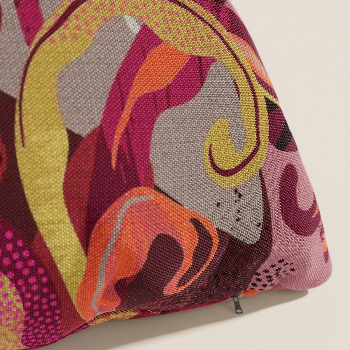 Un primo piano di Joy, un cuscino divitt.sbs a fantasie multicolor rosse in fresco cotone impermeabile, perfetto per cuscini lavabili 45x45 cm. Elegante e pratico, con zip nera sul bordo.